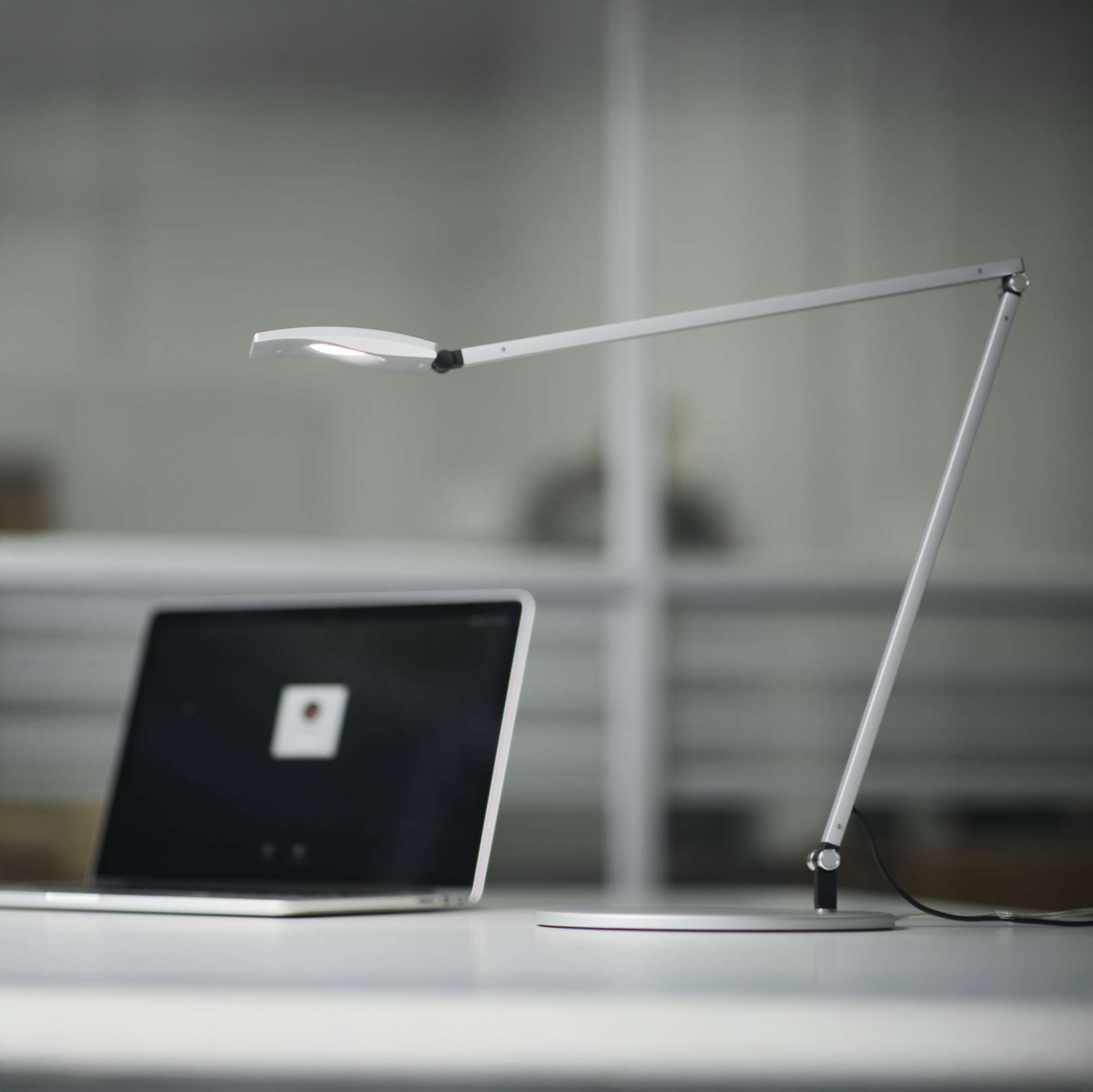 Mosso Pro Desk Lamp in silver finish on office desk beside laptop