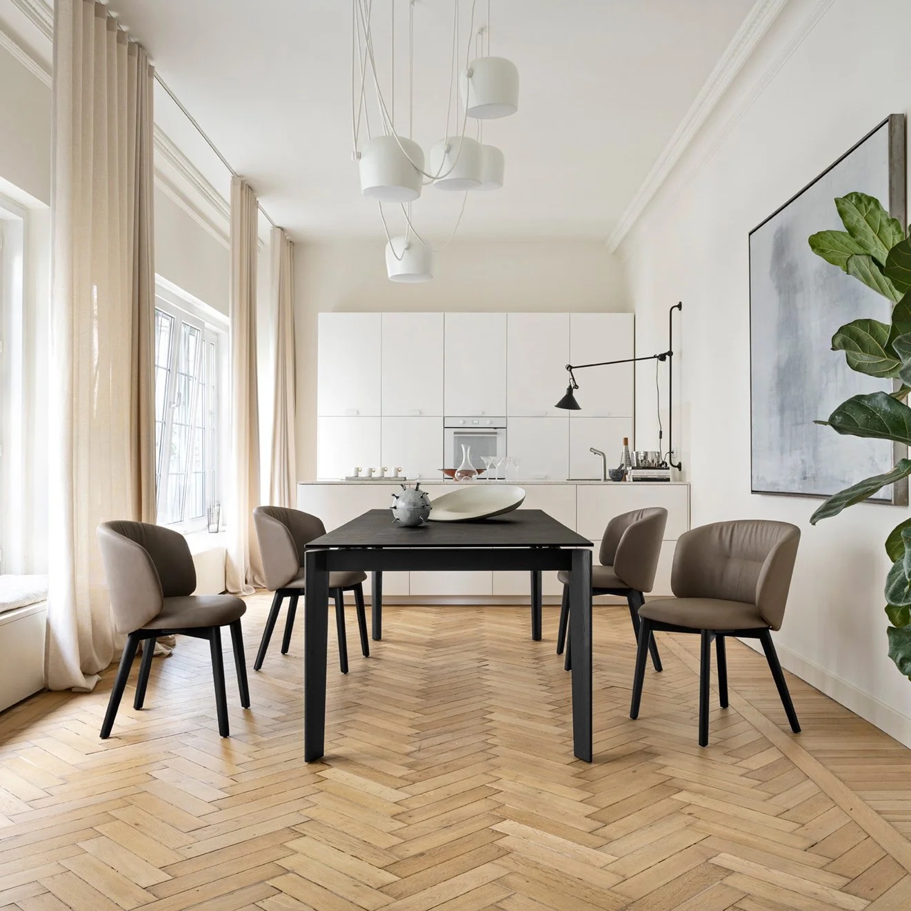 Dogma Table in an elegant dining room with beige chairs and modern pendant lights