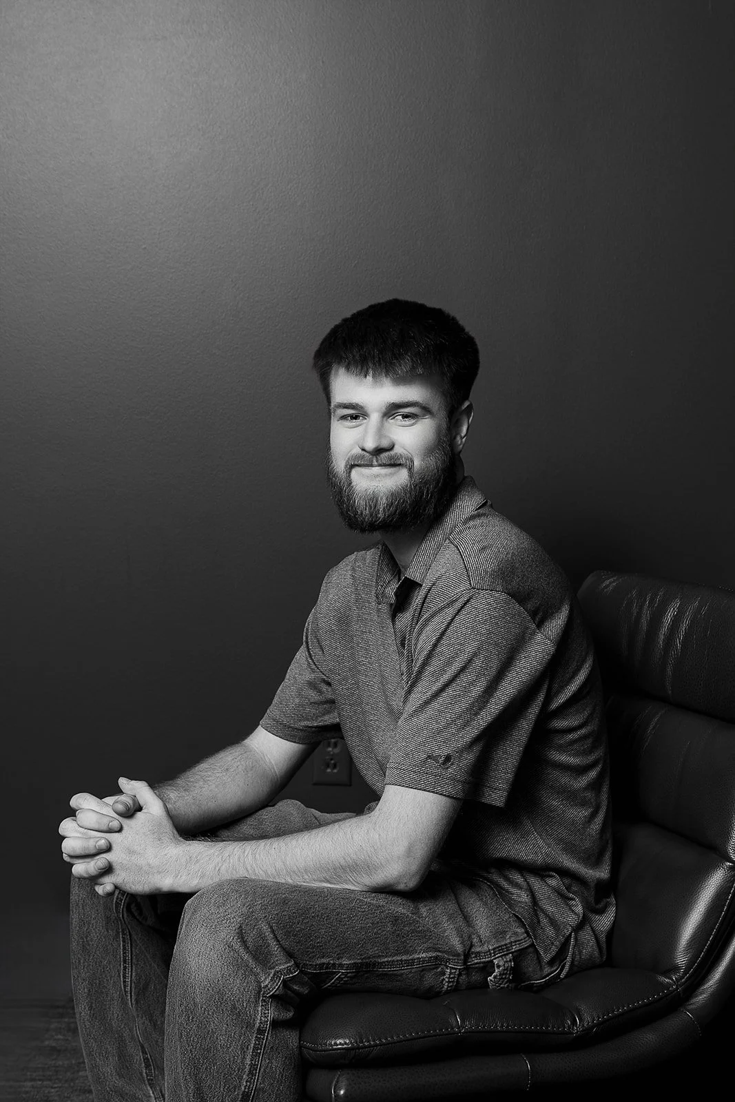 Man sitting in modern chair, smiling with hands folded