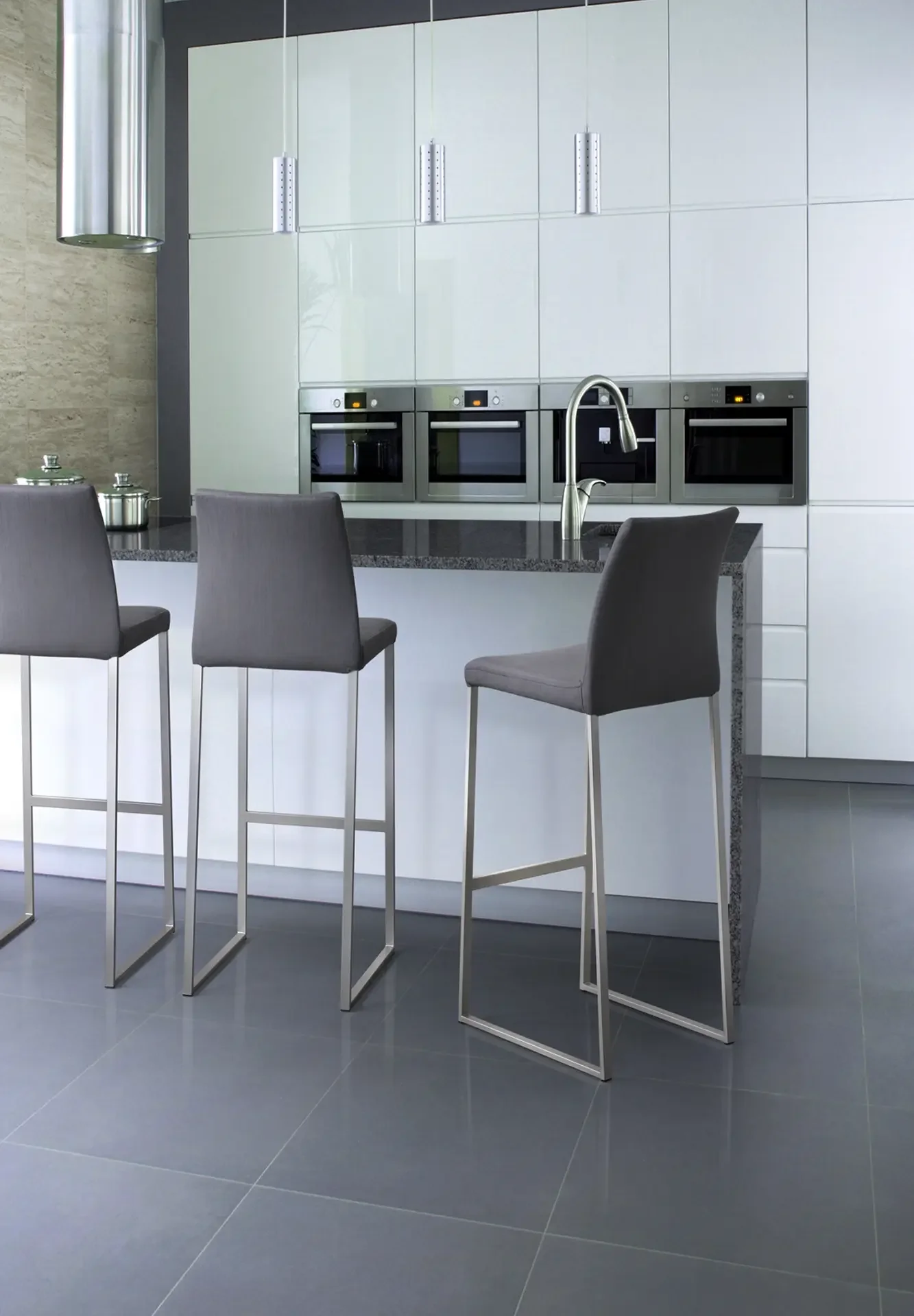Modern kitchen with multiple Trica Curvo Counter-height Stools in grey upholstery and metal legs