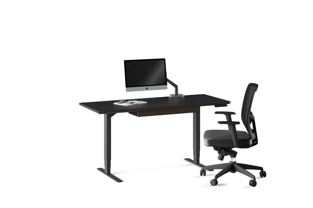 Side-angle view of desk with seated office chair and wood top desk surface