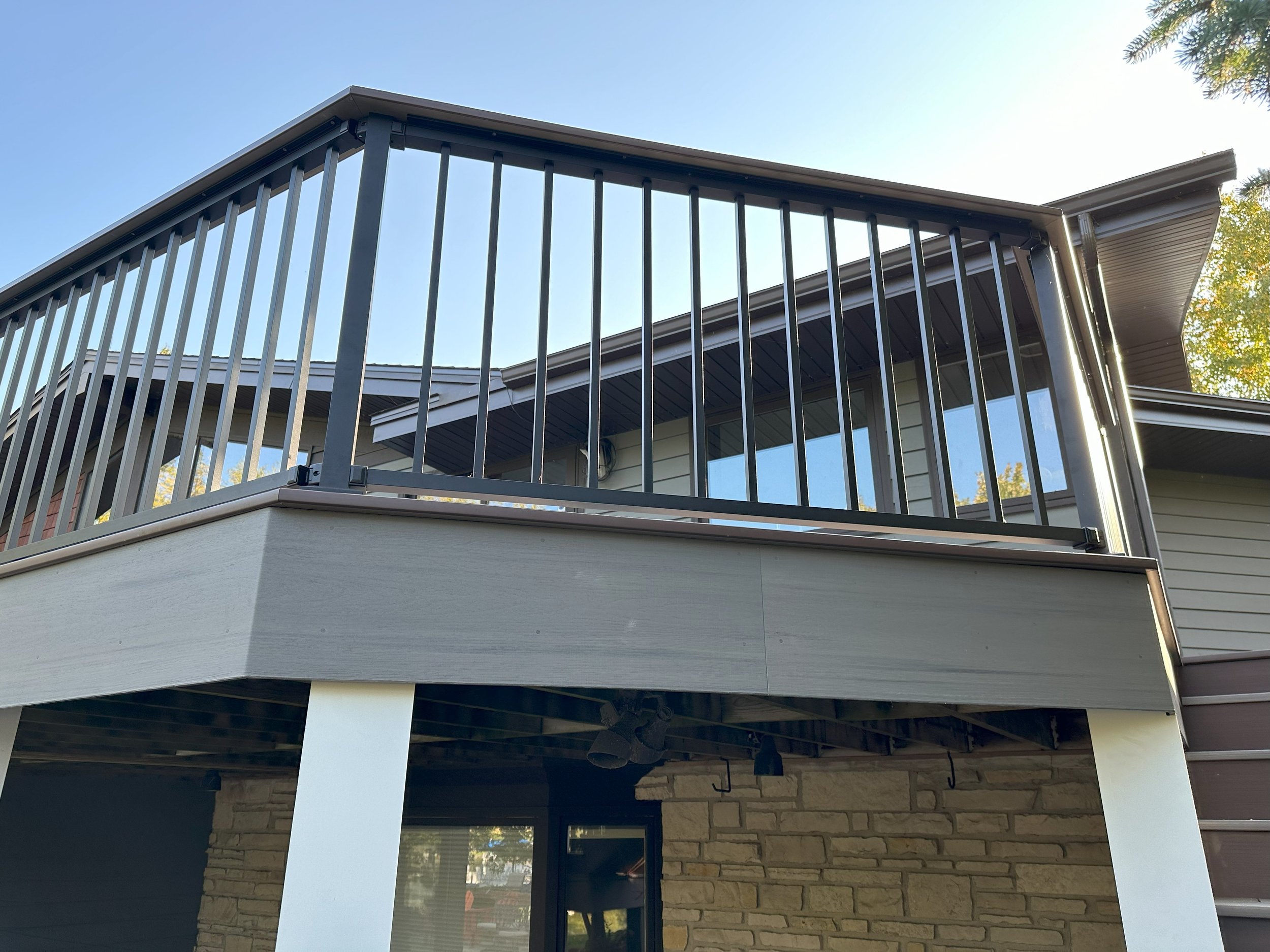 Outdoor wooden deck with metal railing on a modern house.