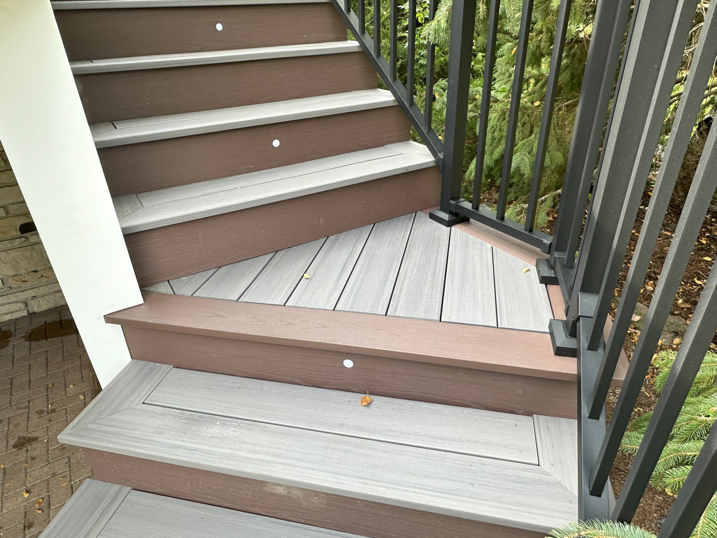 Outdoor staircase with composite decking and black metal railing.