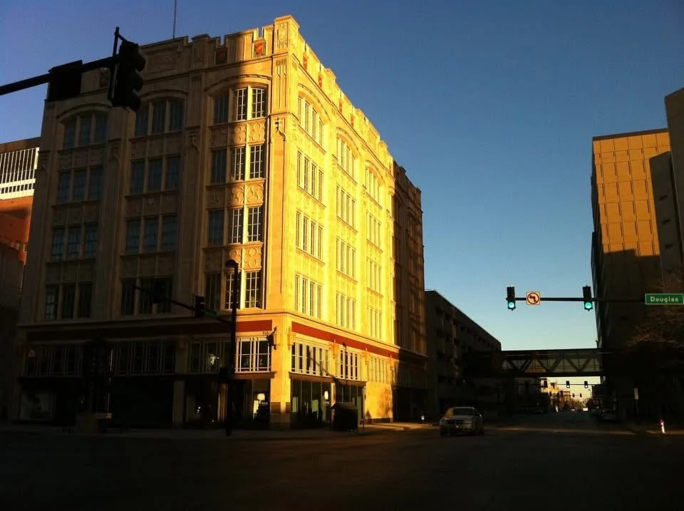 Sunlit historic building at a street corner with traffic lights and a street sign that says Douglas.