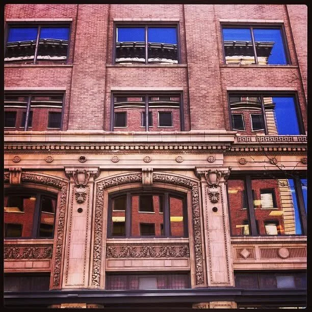Close-up of a historic brick building with ornate stone window frames and decorative architectural details.