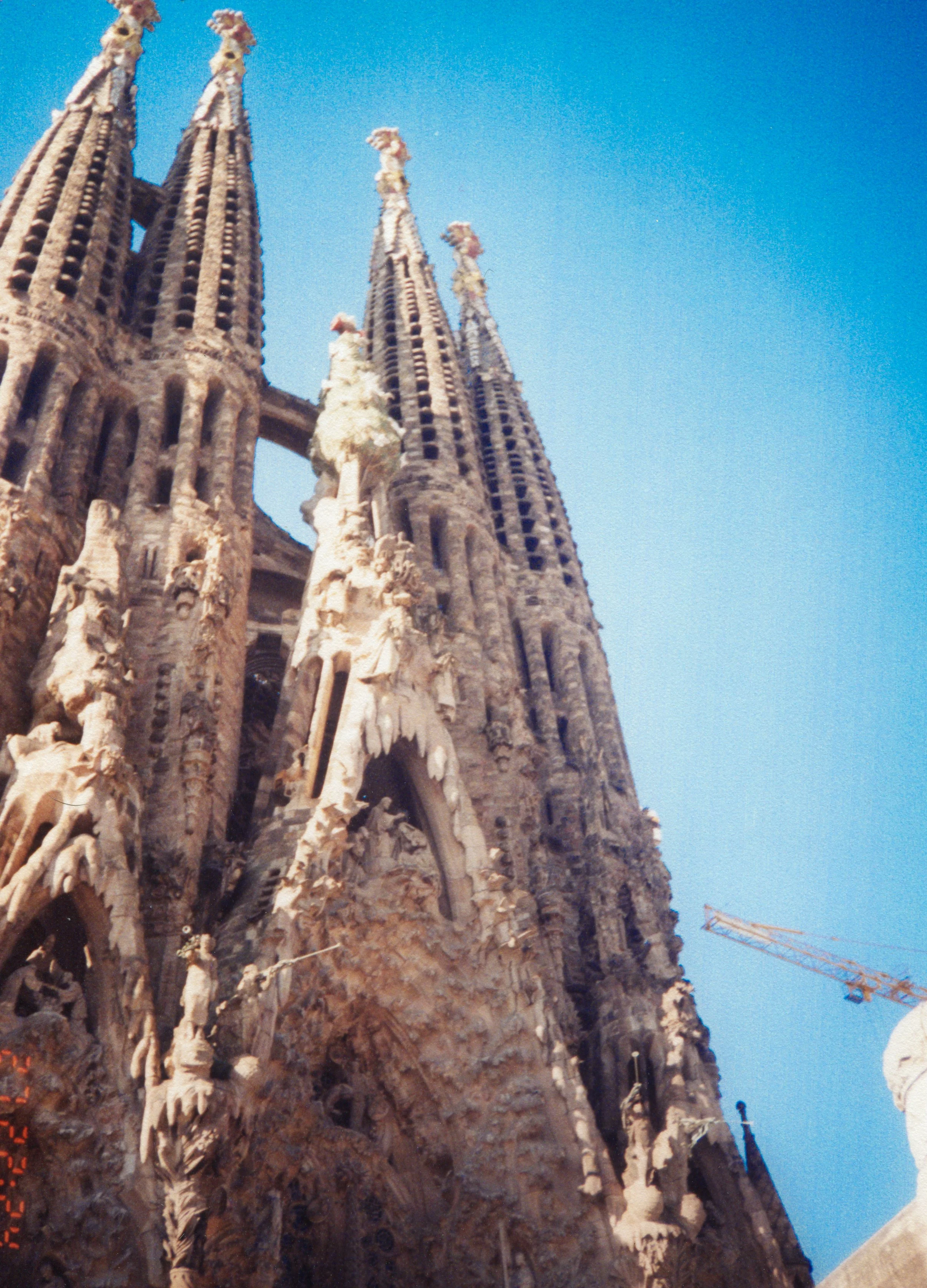 Close-up view of the Sagrada Familia church in Barcelona, Spain, showing its intricate Gothic and Art Nouveau architectural details with a clear blue sky in the background.