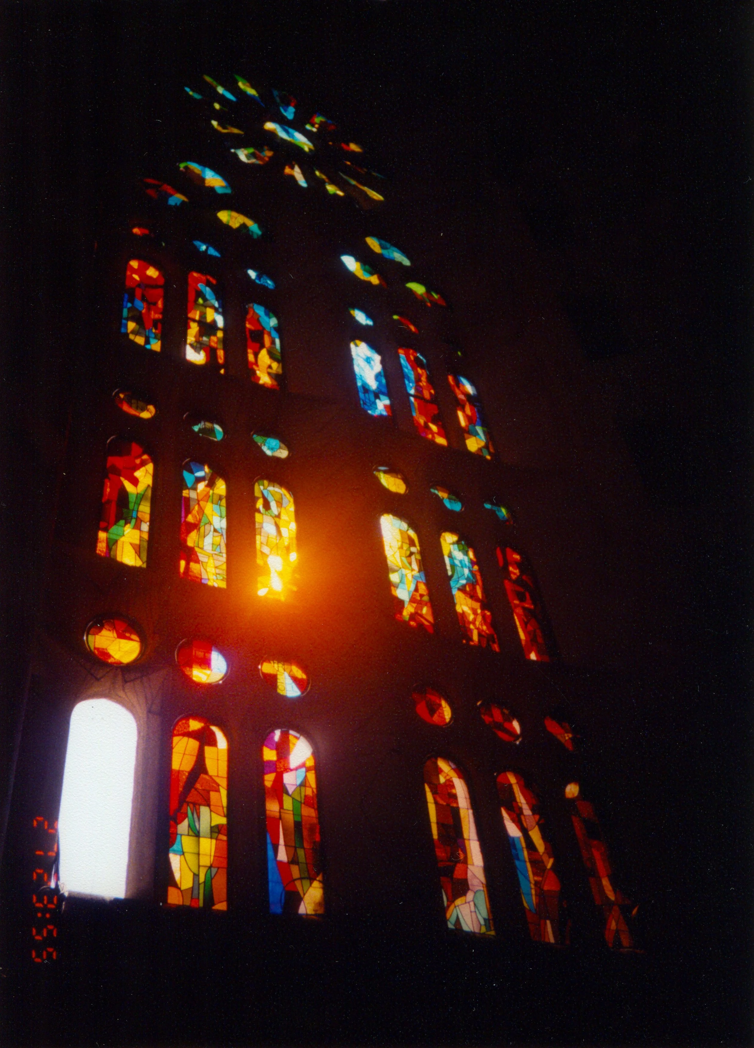 Colorful stained glass windows shining with light inside a dark space.