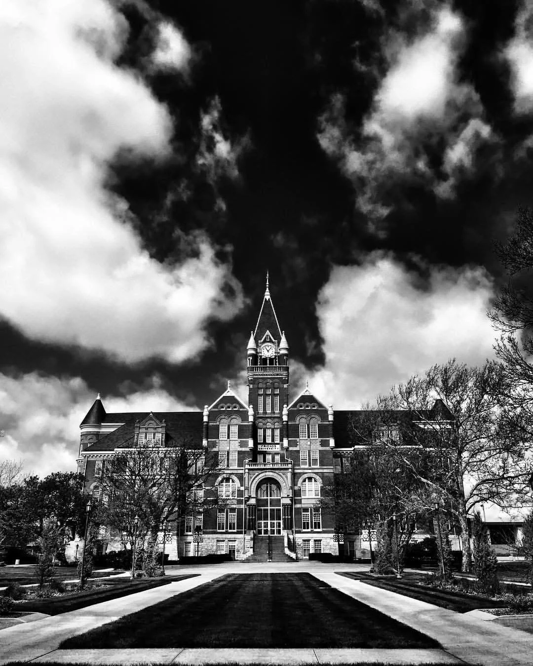 A large historic building with a clock tower under a cloudy sky.