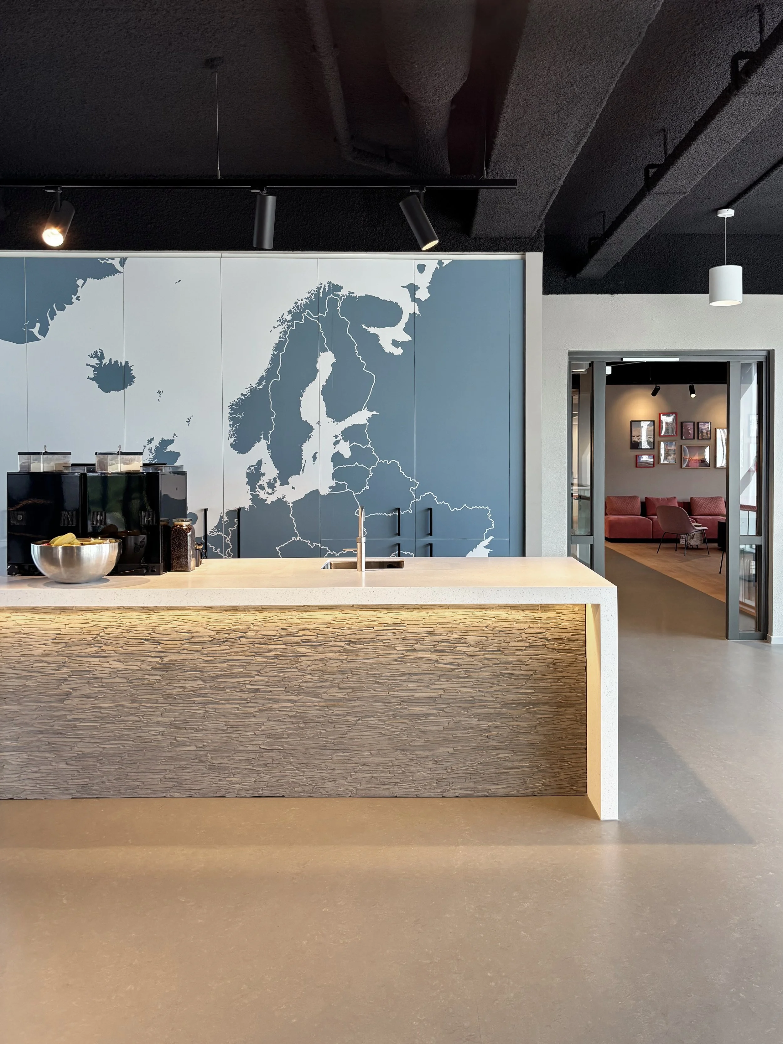 Coffee bar with stacked stones and map wall at Northbound Travel office, Naarden, designed by Meeder Ontwerpers.