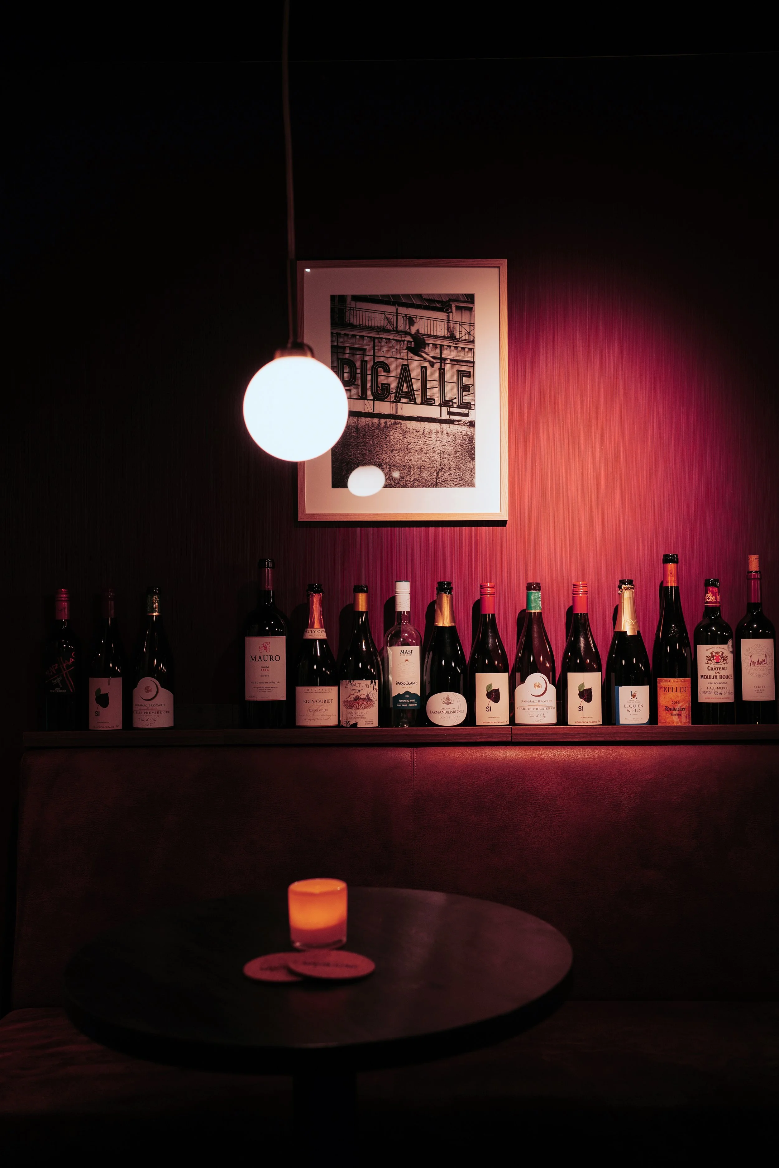 Wine bar with bordeaux wall, bottle display and wall lighting at Vermeers Wijnkamer, Amsterdam, redesigned by Meeder Ontwerpers X Studio Michiel Wijnen.