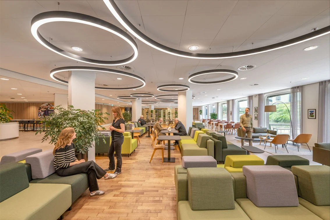Green banquette seating with circular lighting in The Tasting Room at Rabobank Headquarters Utrecht, designed by Meeder Ontwerpers X OIII Architecten.