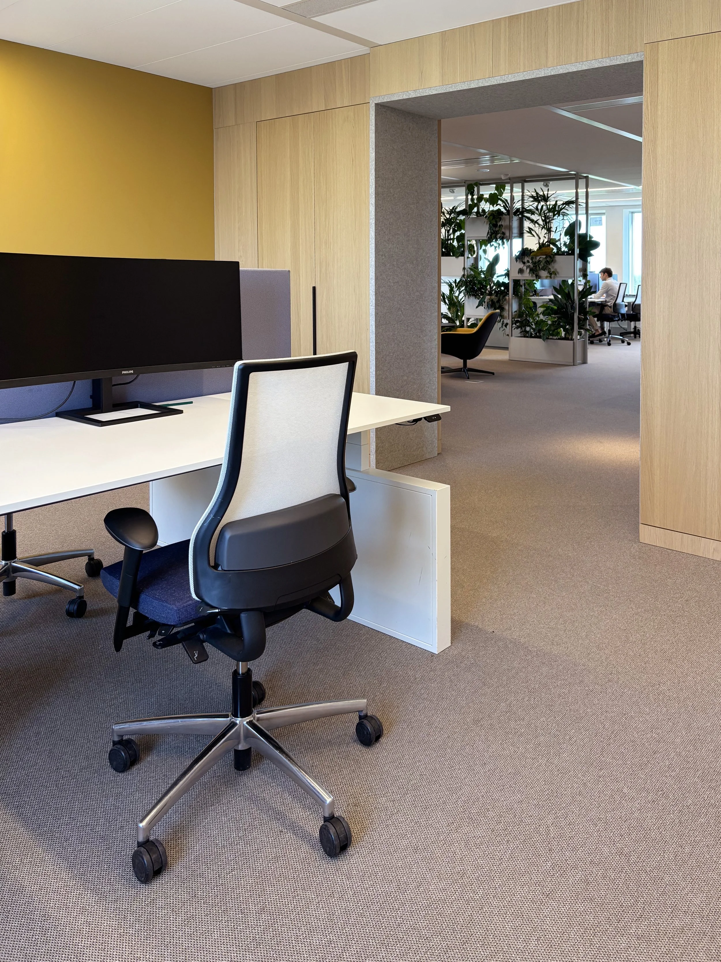 Workplace with yellow wall and see-through view at Garbe Institutional office, Zuidas Amsterdam, designed by Meeder Ontwerpers.