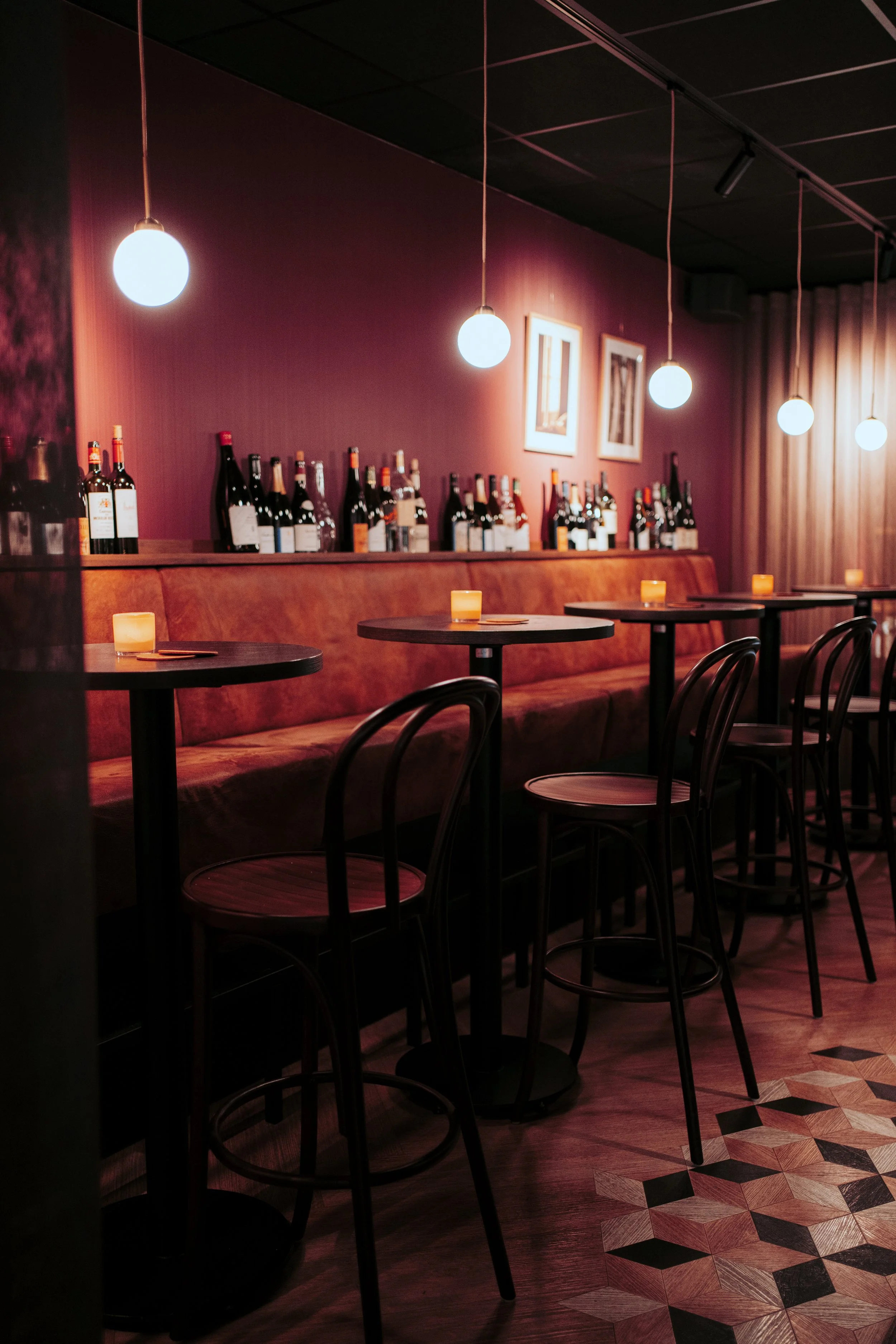 Wine bar with wall seating, bottle display and pendant lighting at Vermeers Wijnkamer, Amsterdam, redesigned by Meeder Ontwerpers X Studio Michiel Wijnen.