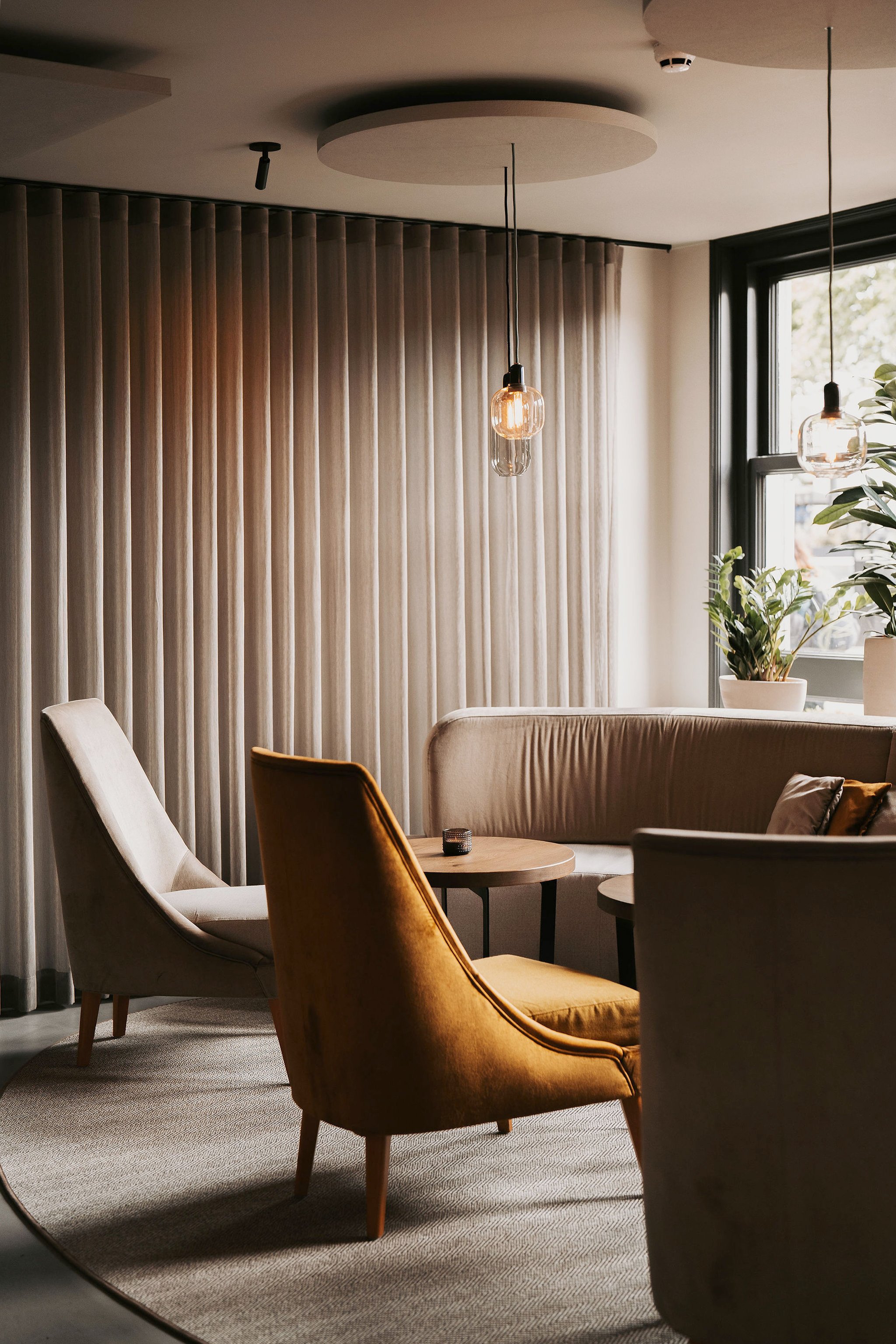 Armchairs by window with curtains and plants at Restaurant Vermeer, Amsterdam, redesigned by Meeder Ontwerpers