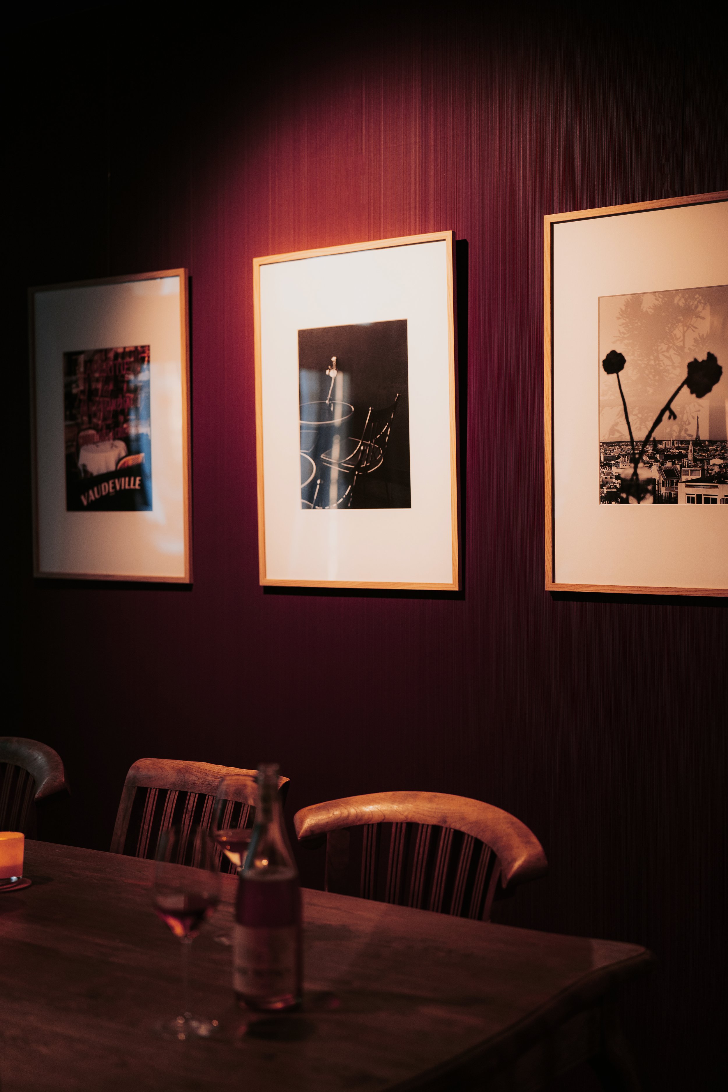 Wine bar with bordeaux wall and Paris-inspired artwork at Vermeers Wijnkamer, Amsterdam, redesigned by Meeder Ontwerpers X Studio Michiel Wijnen.
