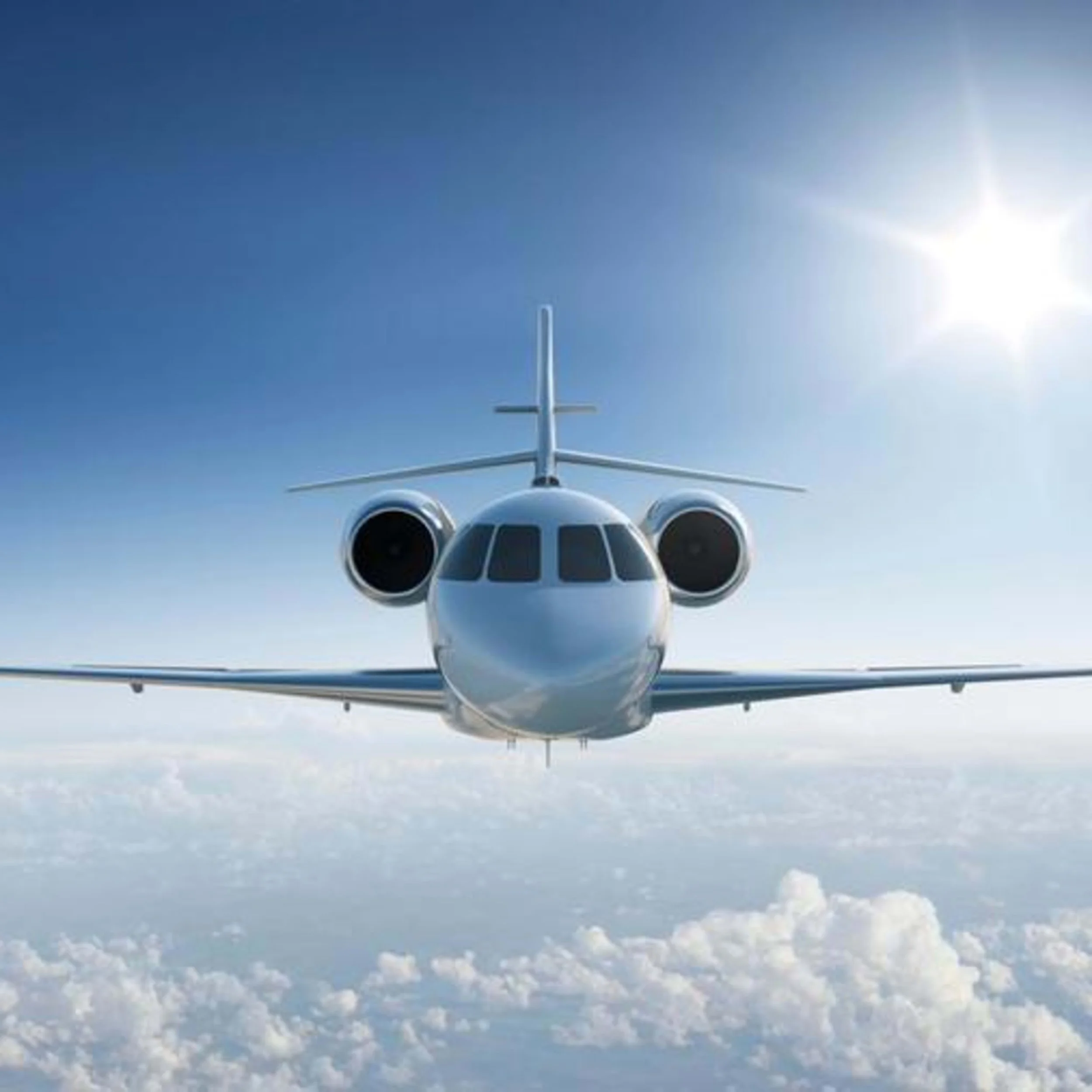 A private jet flying above the clouds with the sun in the sky.