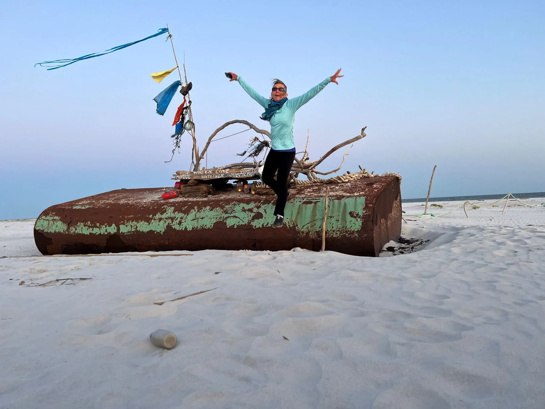 The image shows Babette jumping from a boat embedded in the sand. She was providing performance artwork inspired by an InVision shamanic journey.