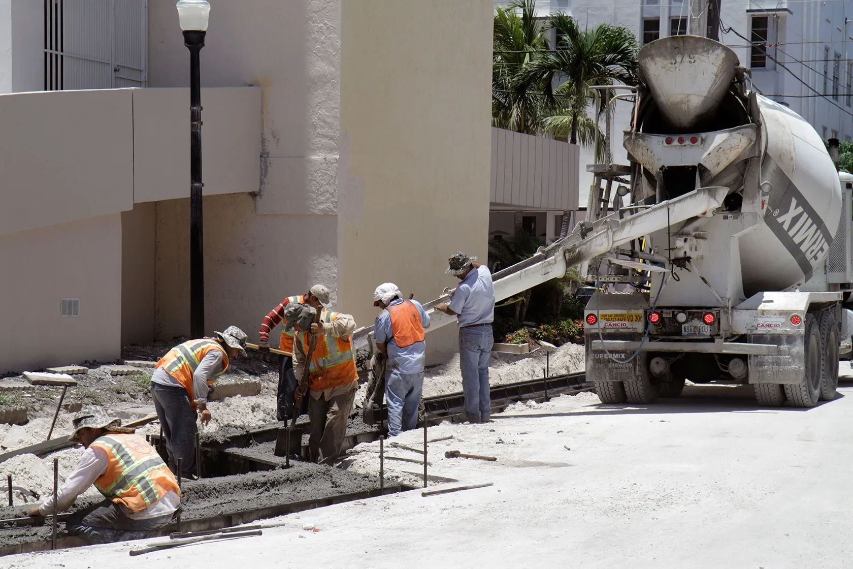 Concrete crew placing and finishing a slab beside a mixer truck