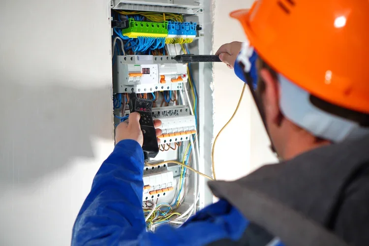 Electrical technician testing circuits inside a commercial breaker panel