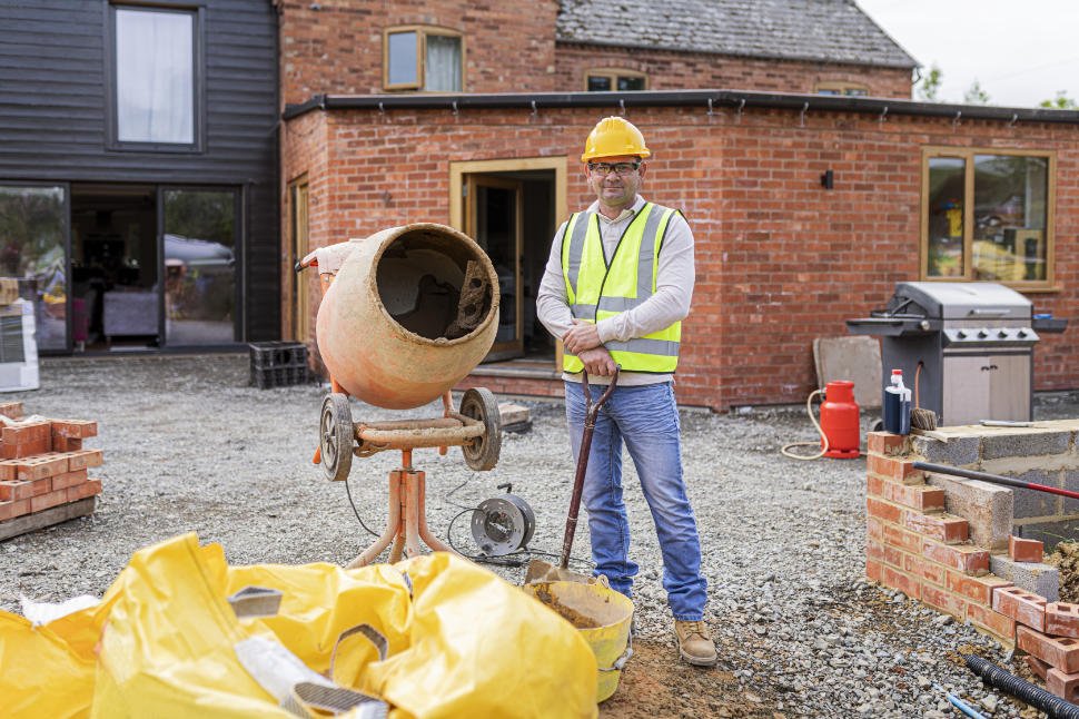 Concrete contractor standing beside mixing equipment at a residential jobsite