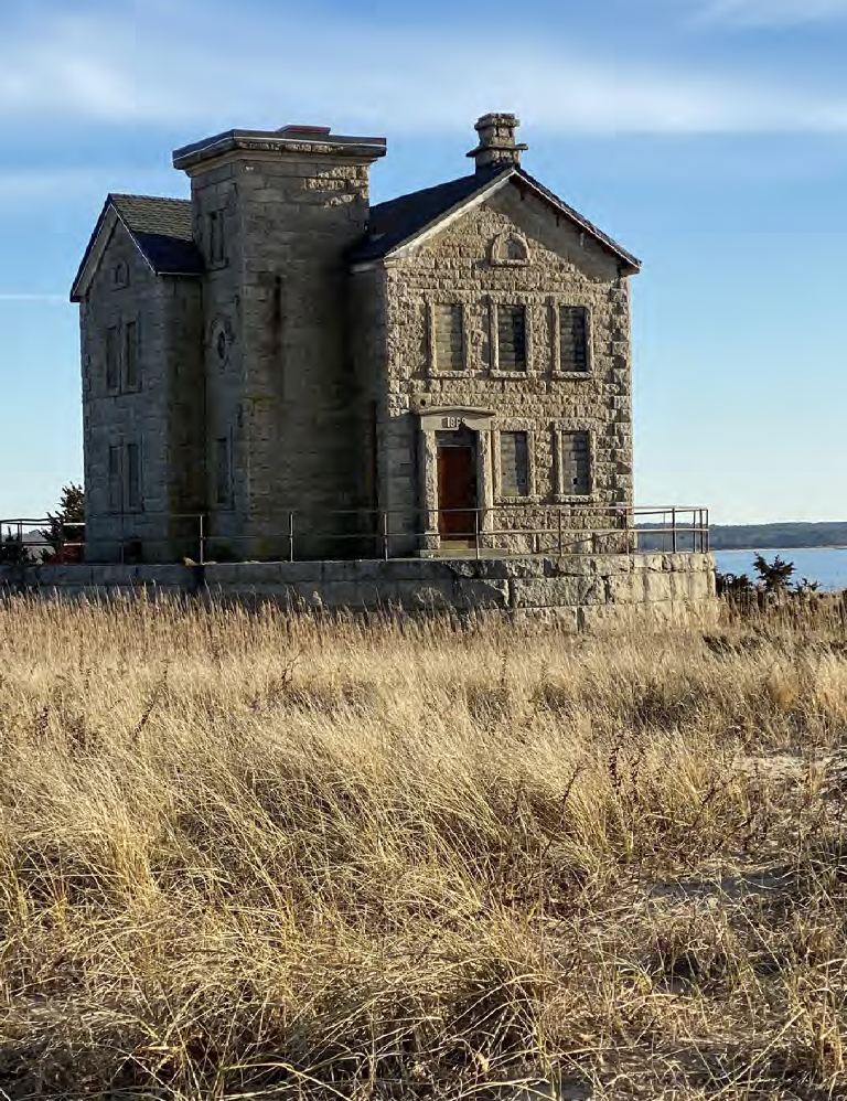Stone lighthouse on a grassy field with ocean view