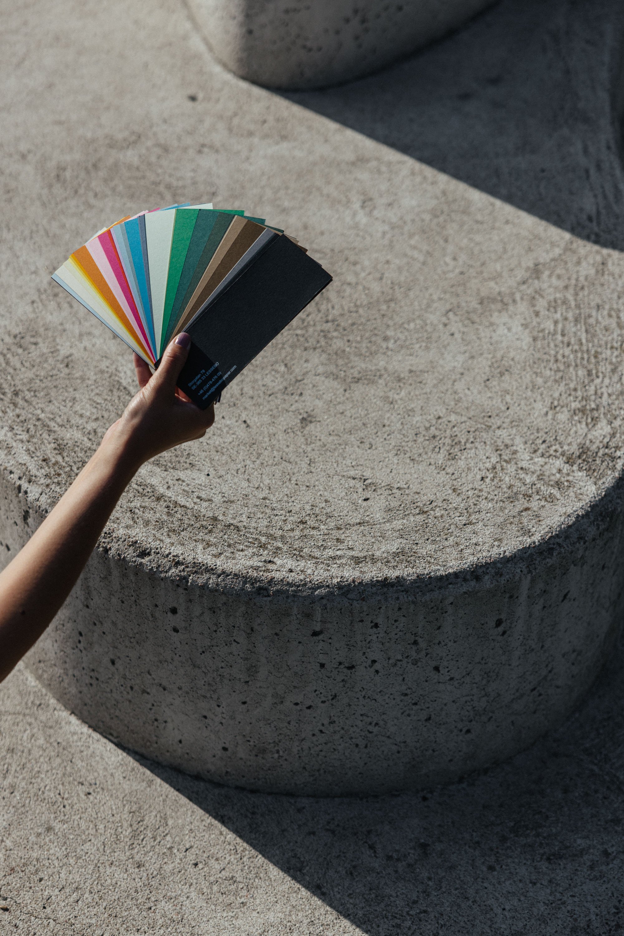 Farbfächer von Papiermuster vor Betontreppe in Sonnenlicht