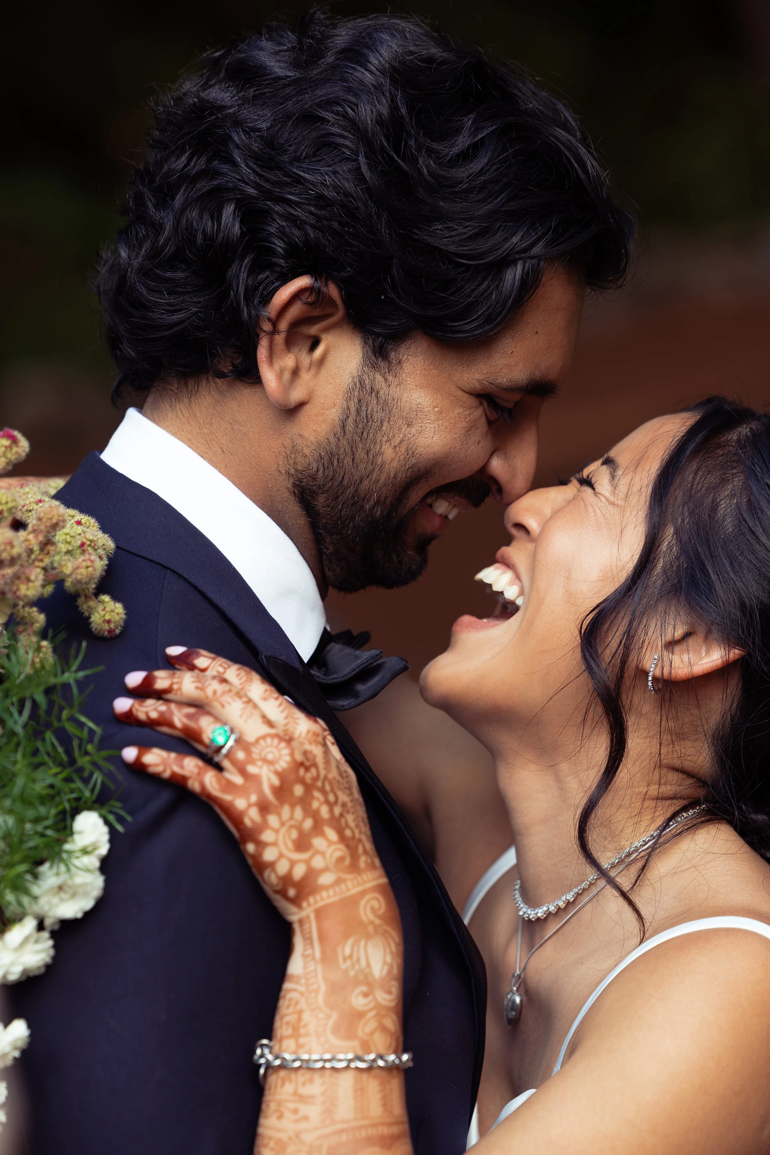 A couple shares a close, joyful moment, their faces near each other, smiling with eyes closed, surrounded by flowers, with a blurred background. Traditional Indian wedding, Oregon Wedding photographer, Wedding photographer near me, Portland Oregon