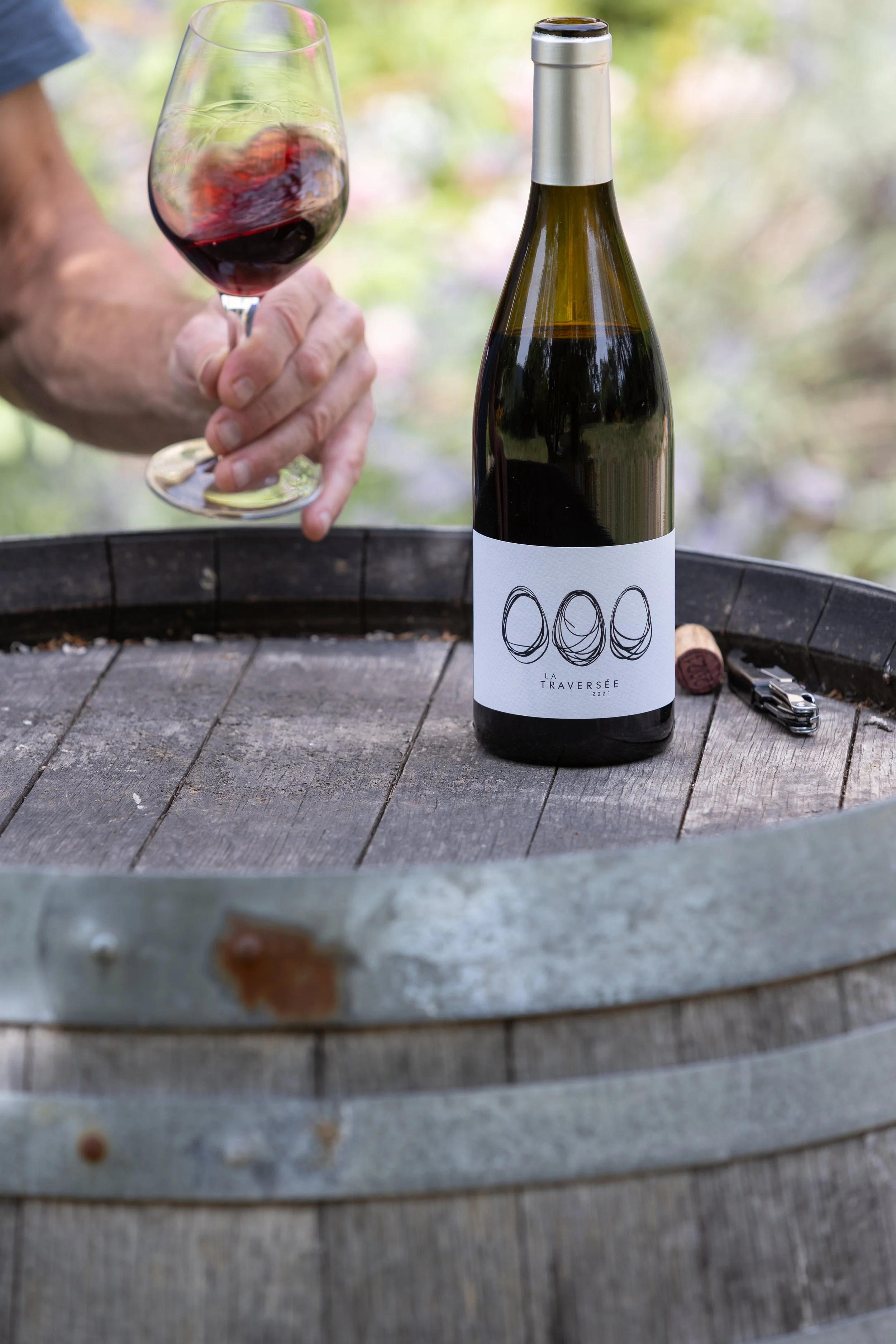 Pouring a glass of La Traversée wine beside an oak barrel in the Terrasses du Larzac wine region