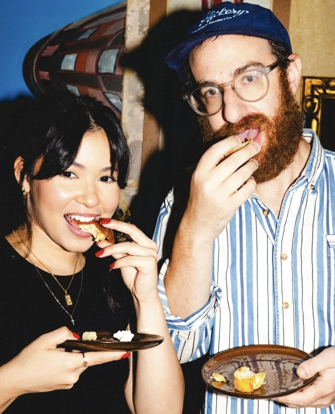 A woman and a man enjoying dessert and snacks together, both with plates of food in their hands
