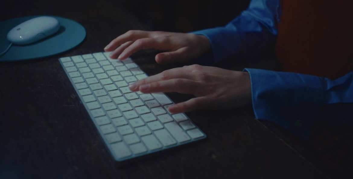 Person typing on a computer keyboard in low light.