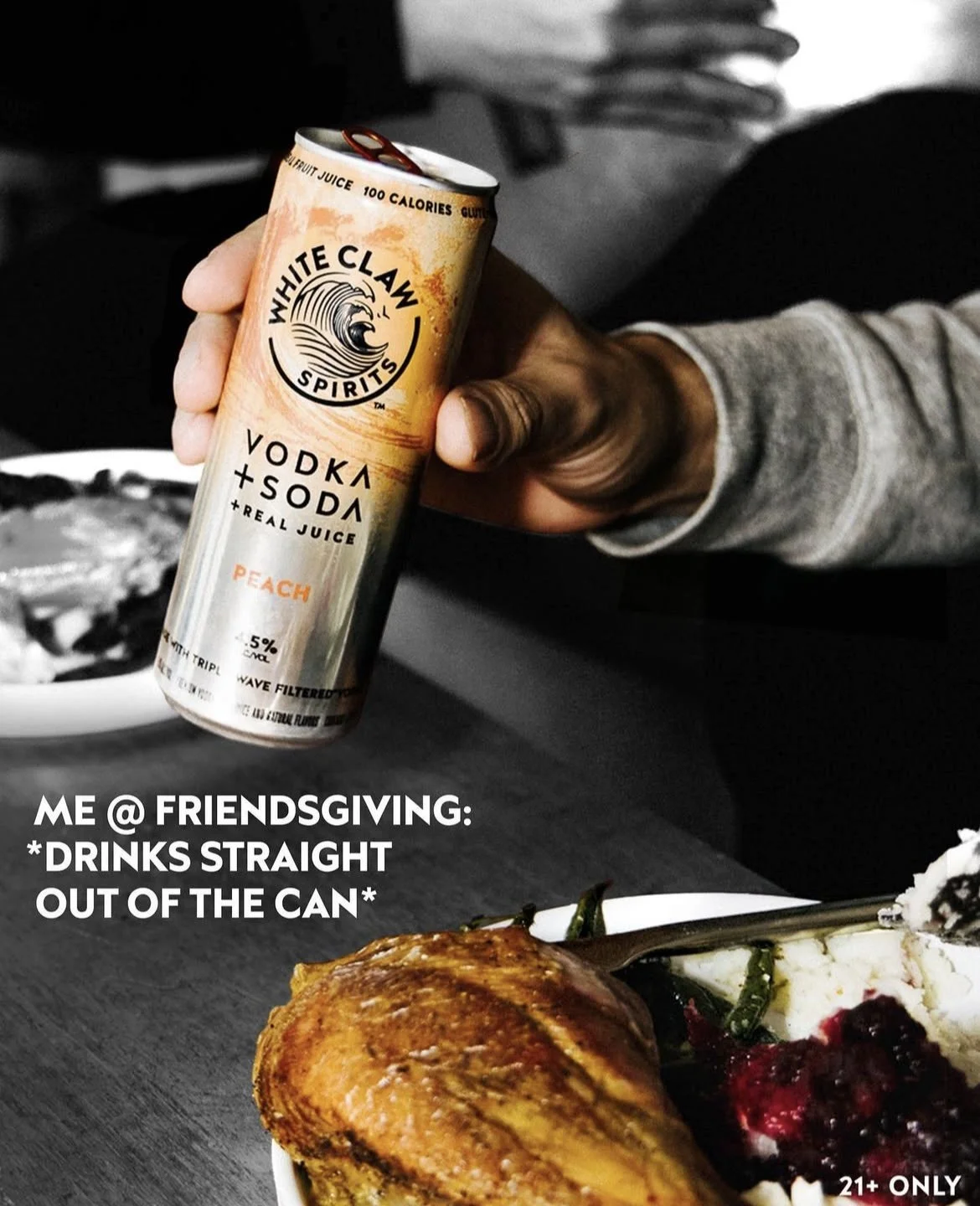 A hand holding a can of White Claw vodka+soda peach flavored alcoholic beverage. The background shows a plate with food, possibly Thanksgiving dinner, with the caption 'ME @ FRIENDSGIVING: *DRINKS STRAIGHT OUT OF THE CAN*'.