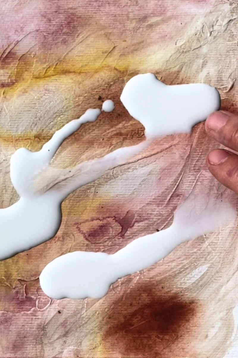 Close-up of fingers spreading white paint across textured layers – an intimate moment of connection during the creation process of "Held by Myself".