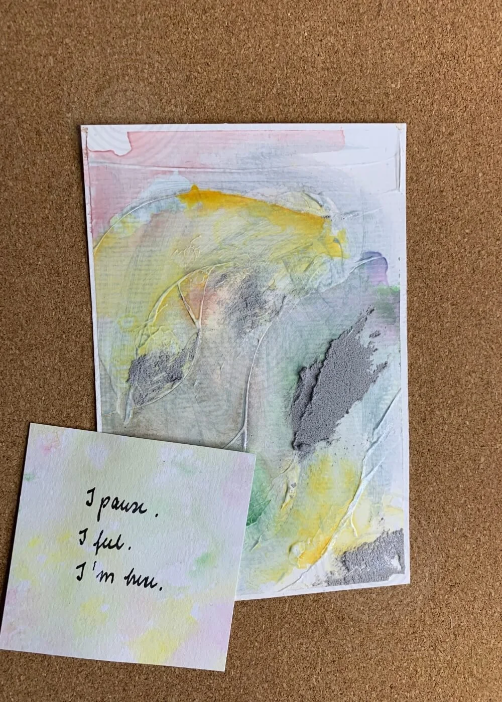 Abstract painting "Between the Seconds No. 4" paired with a handwritten affirmation card reading “I pause. I feel. I’m here.” on a cork background.