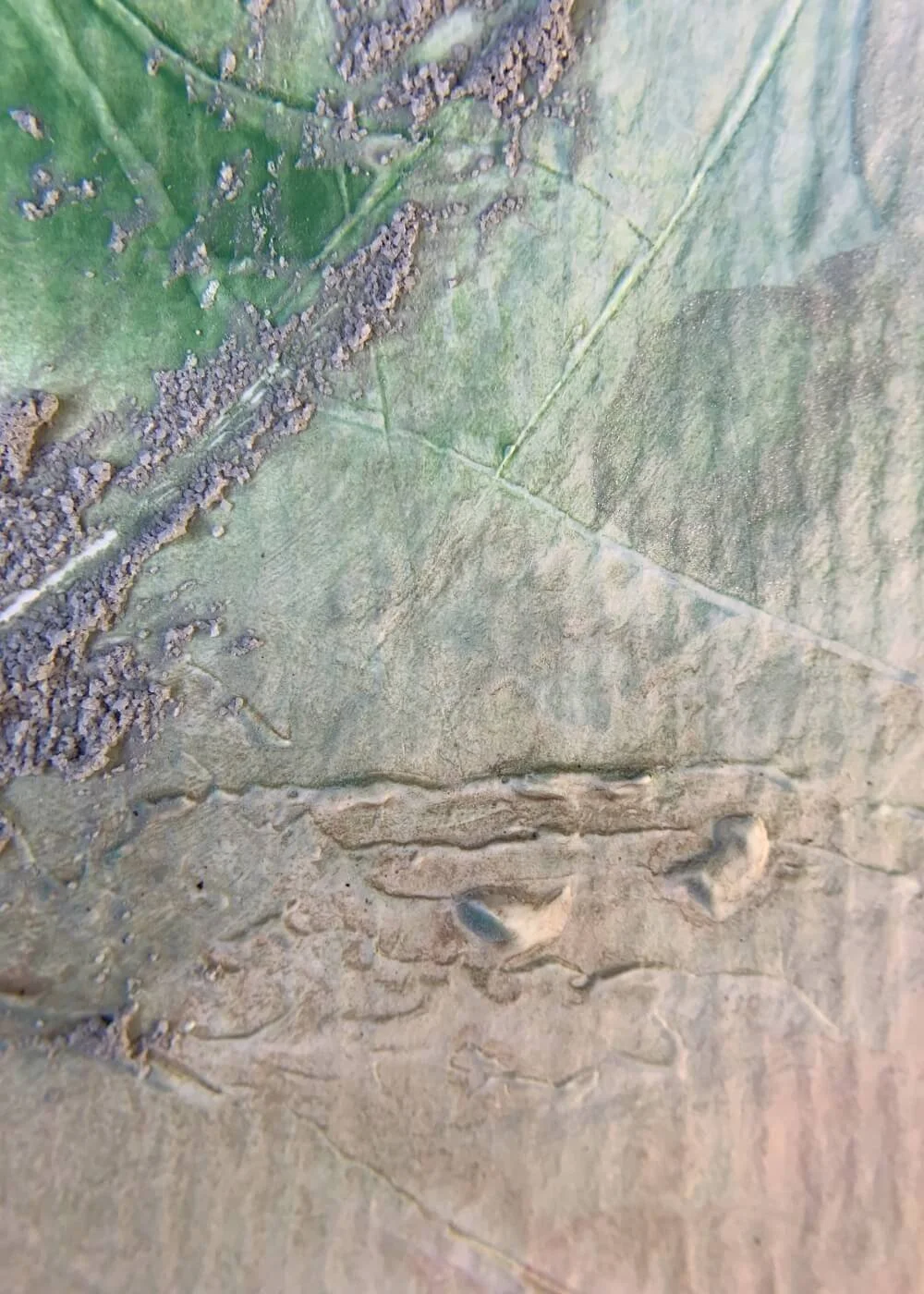 Close-up of textured abstract surface of "Between the Seconds No. 8" showing earthy beige layers with raised patterns and hints of green pigment.