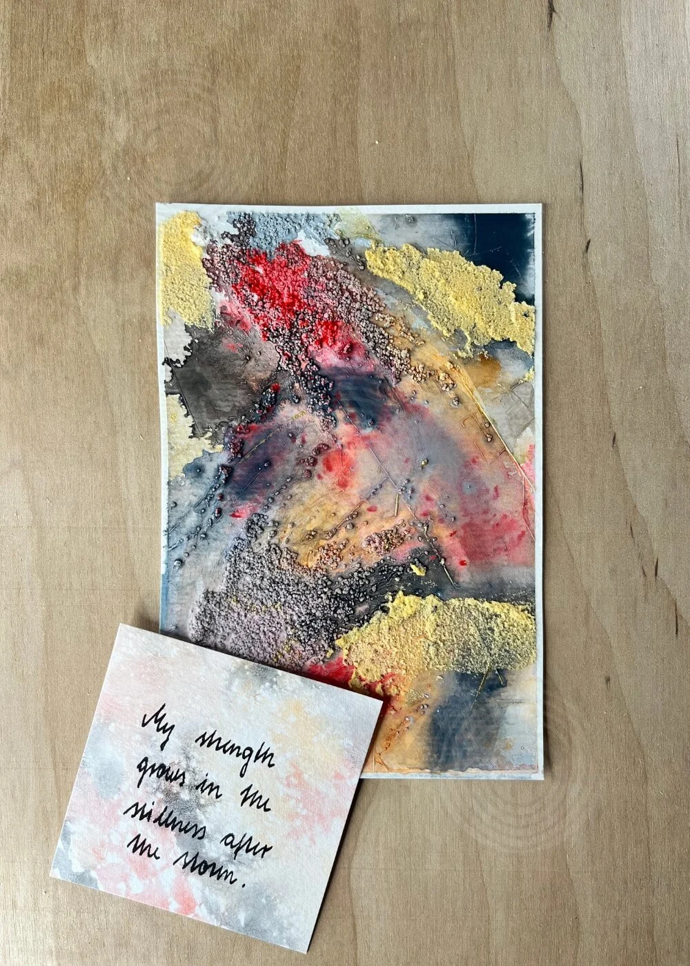 A handwritten card reads “My strength grows in the stillness after the storm.” — the words and colors dissolve into each other like smoke returning to air.