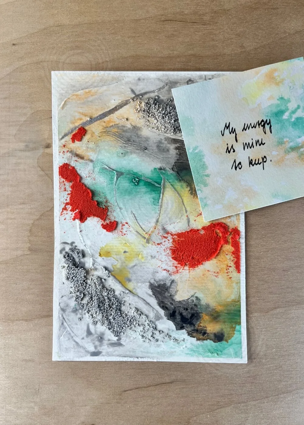 Abstract painting with affirmation card reading “My energy is mine to keep”, textured layers in red, green, yellow, black, and grey.