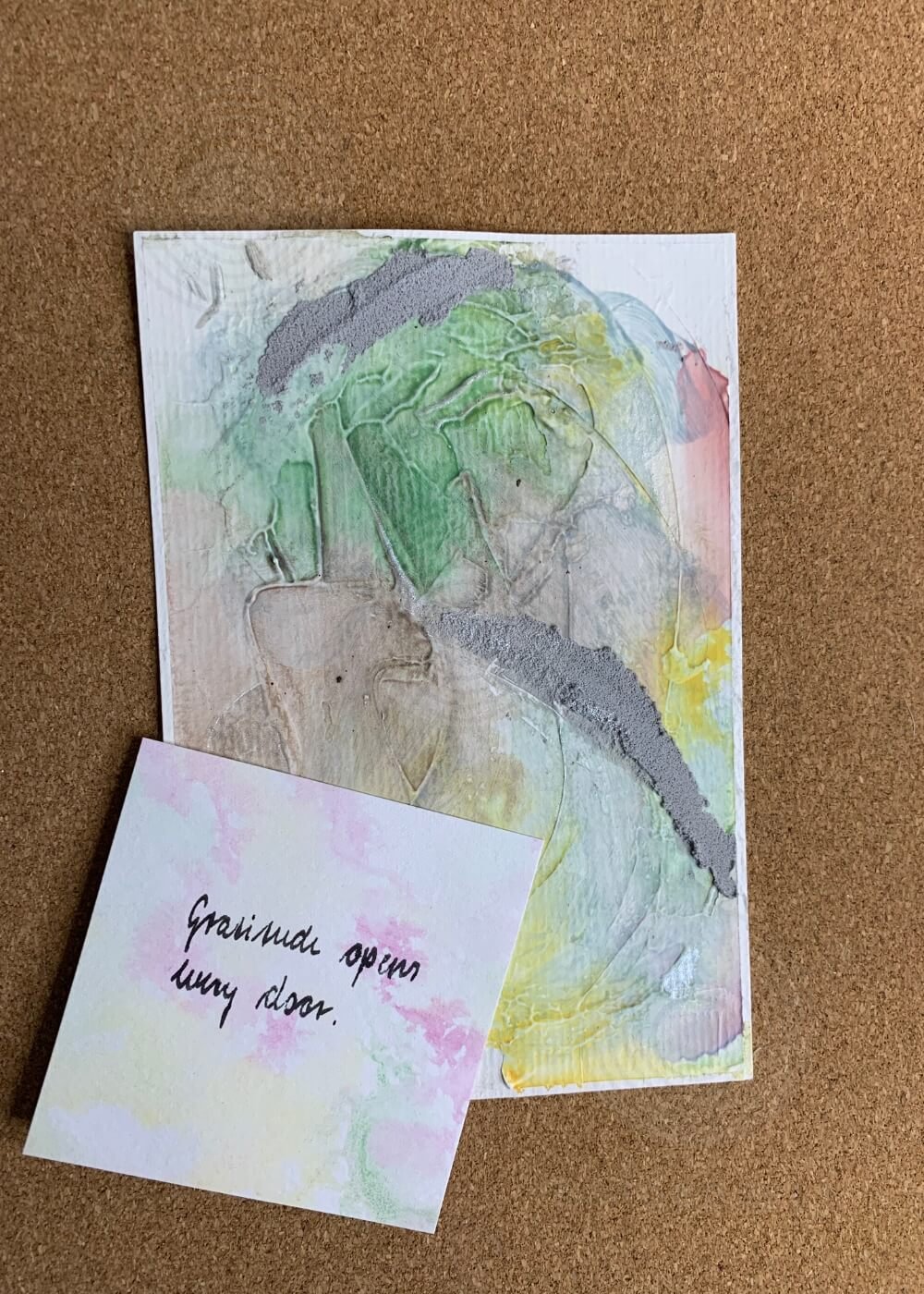 Abstract artwork "Between the Seconds No. 10" in pastel green, yellow and grey with an affirmation card placed on top reading "Gratitude opens every door."