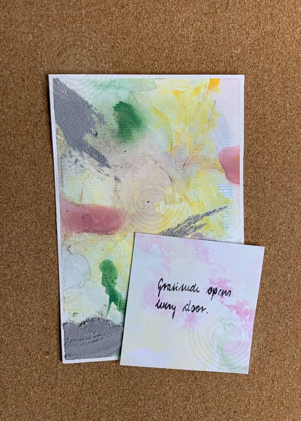 Abstract artwork Between the Seconds – No. 3 displayed with an affirmation card reading “Gratitude opens every door” on a cork background.