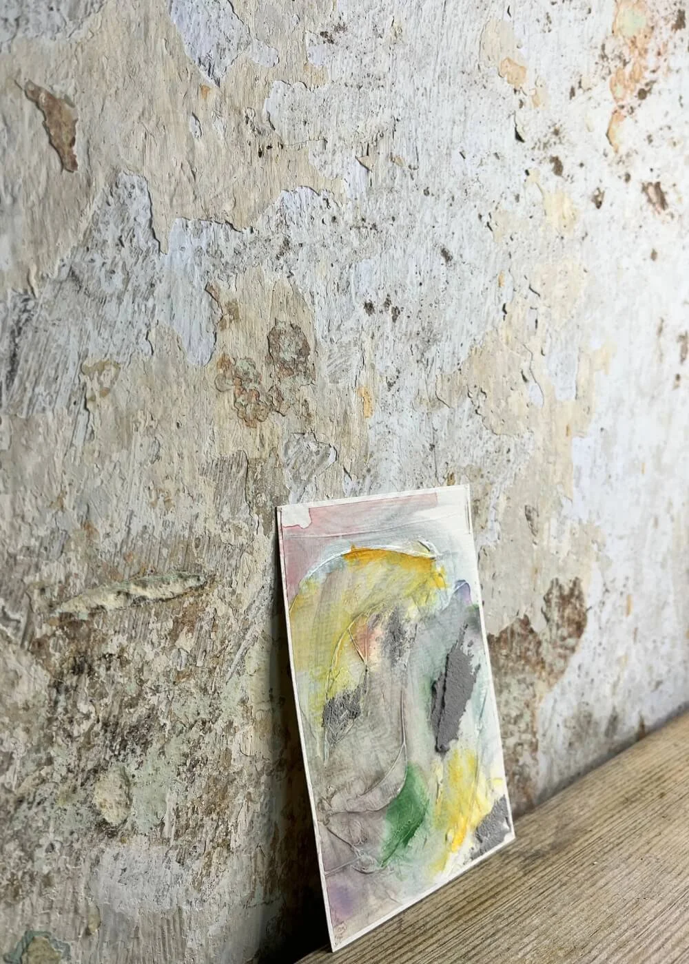 Angled perspective of the artwork "Held by Myself No. 4" , showing layered textures and muted pastel tones of yellow, green, and grey.