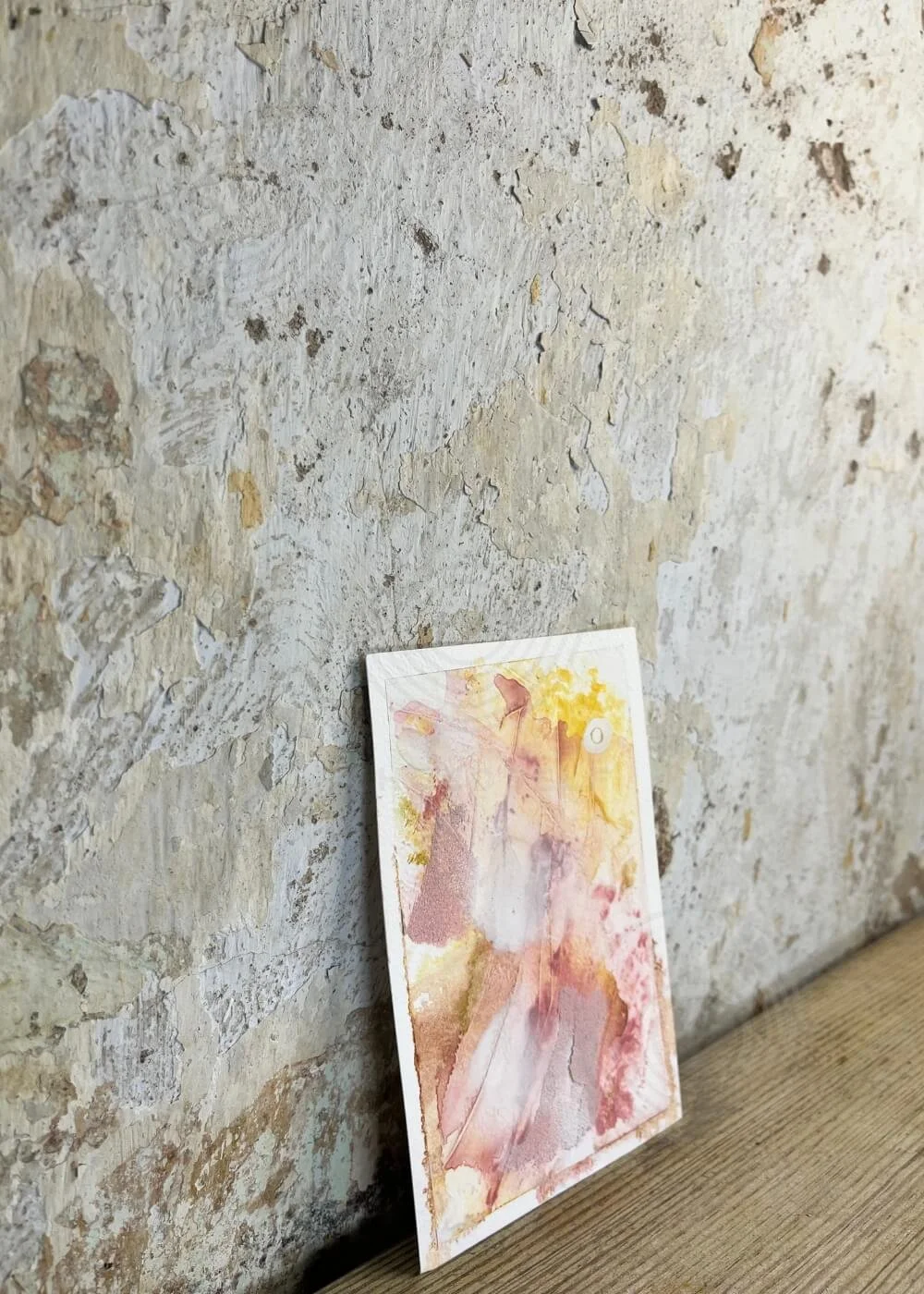 Side view of “Held by Myself No. 7,” a tactile healing artwork in rose, yellow, and earthy tones leaning against a textured wall.