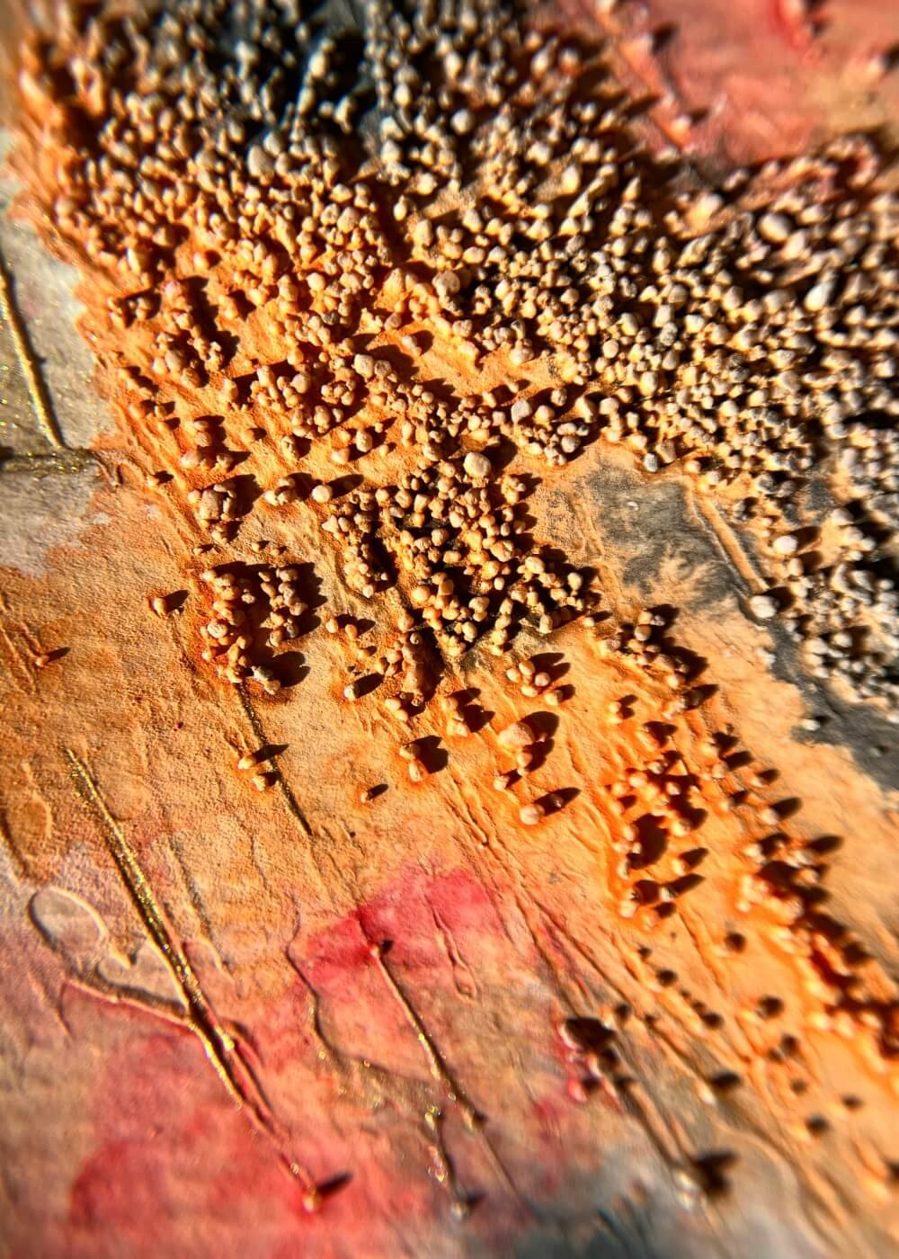 Warm grains of ochre rise through red and charcoal textures — a tactile memory of fire learning how to rest.