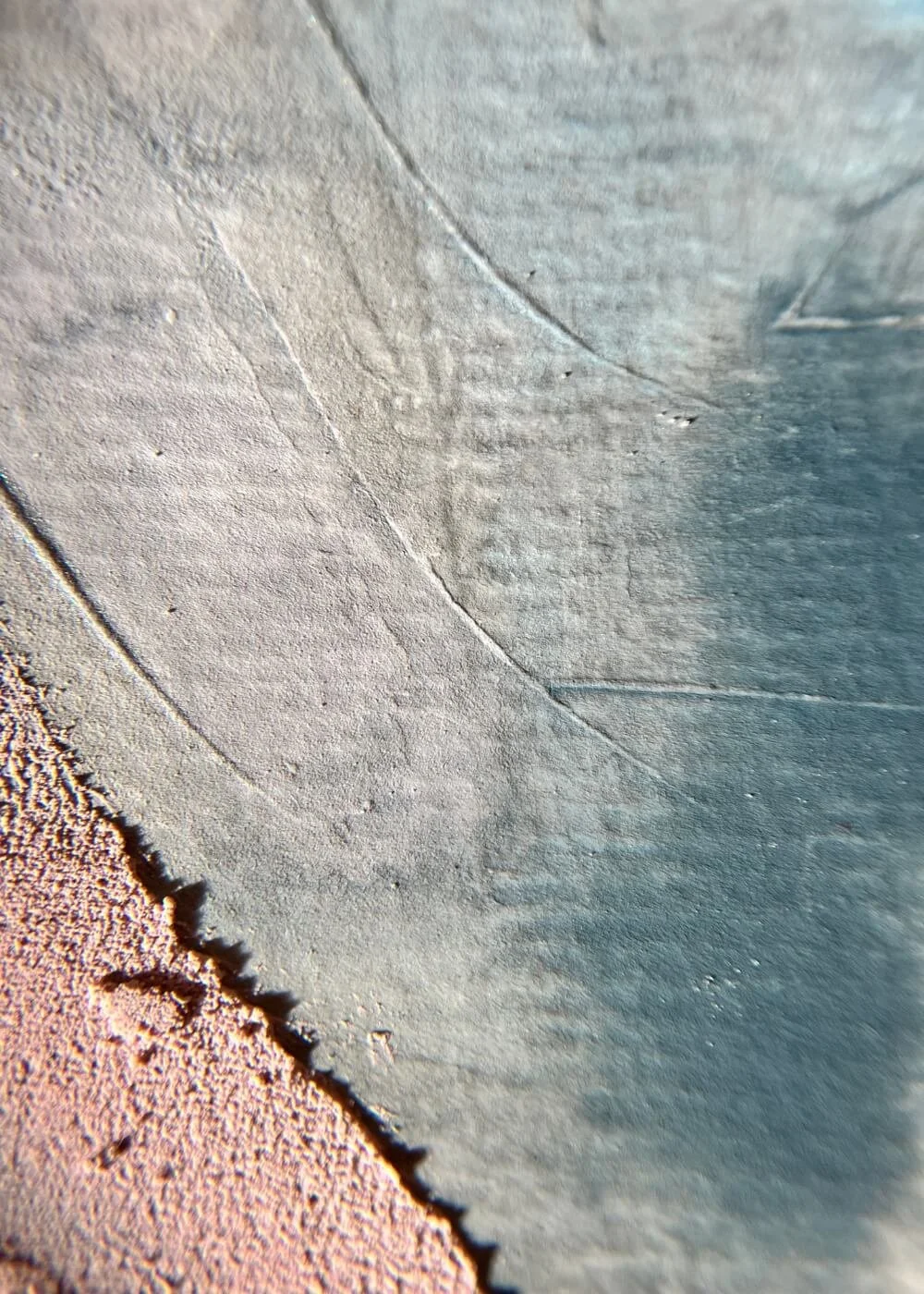 Close-up photograph of teal and pink textures merging softly, highlighting tactile surface depth and the meditative flow within And Everything Turns Translucent.