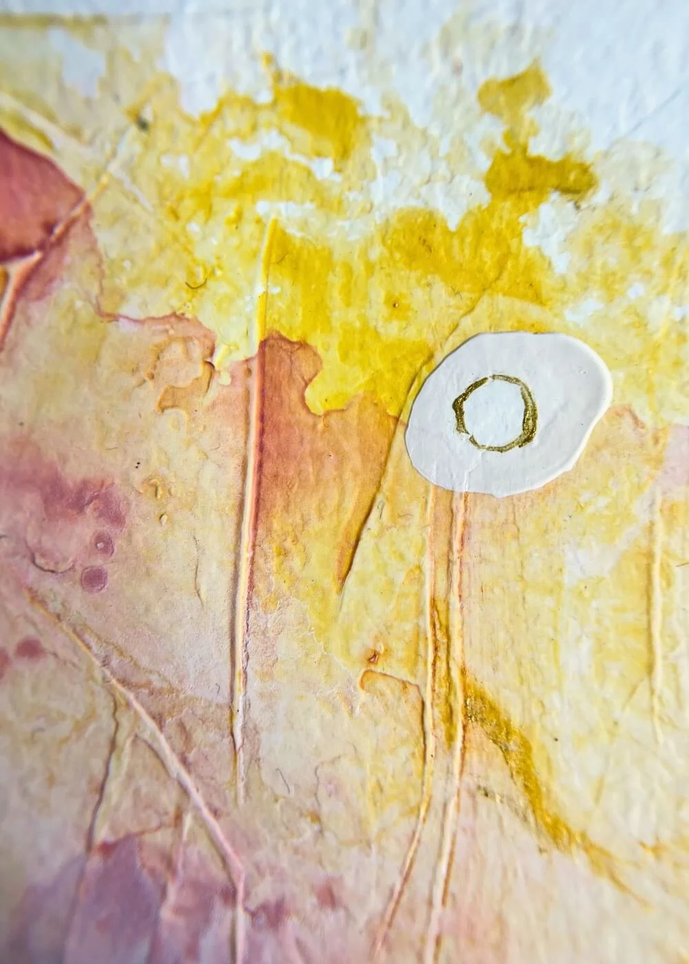 Close-up of abstract artwork “Held by Myself No. 7” showing textured layers in yellow, rose, and cream with a circular white-gold detail.