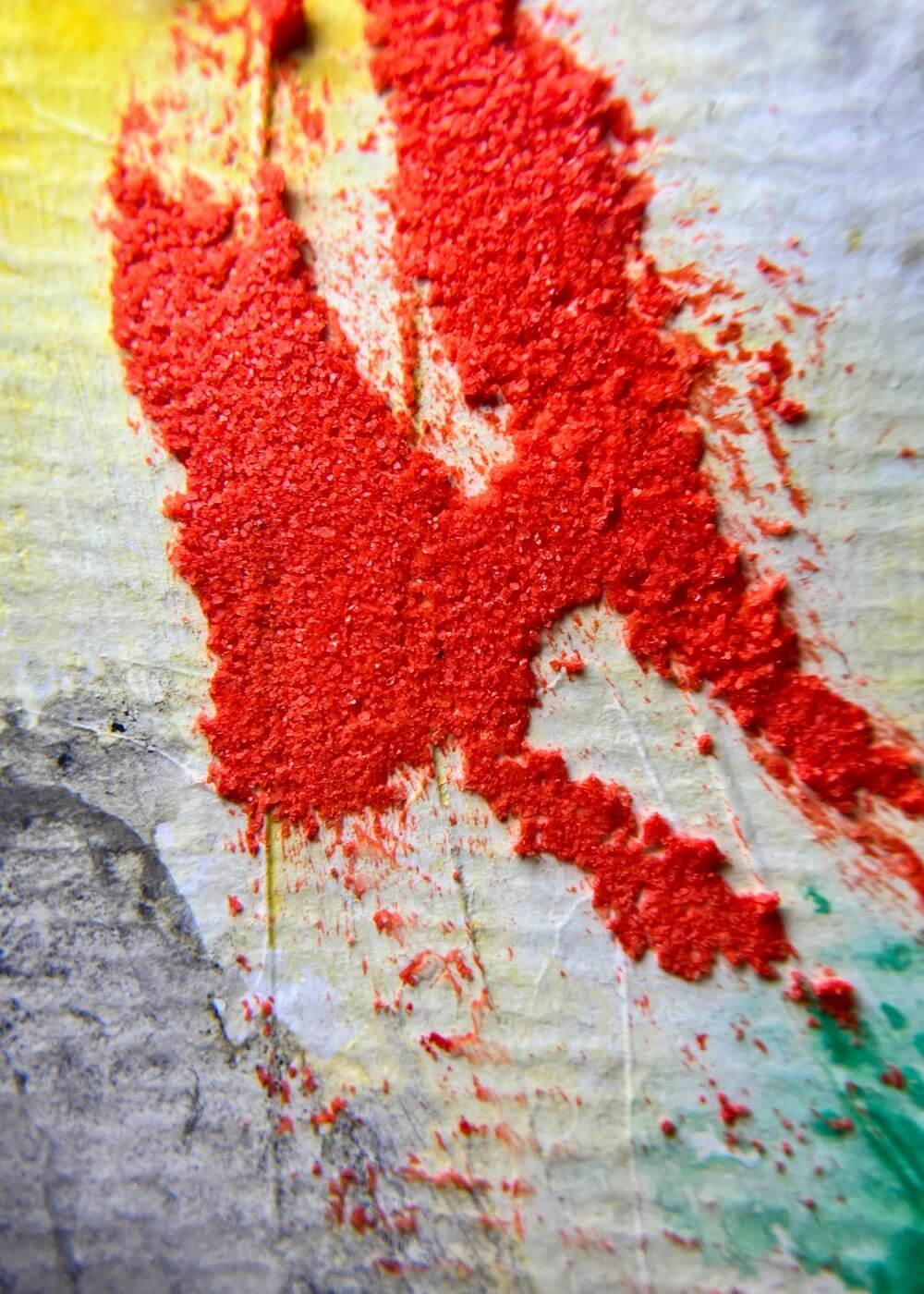 Macro close-up of vivid red textured pigment on abstract artwork "Where I Draw the Line", showing raw detail and layered surface.