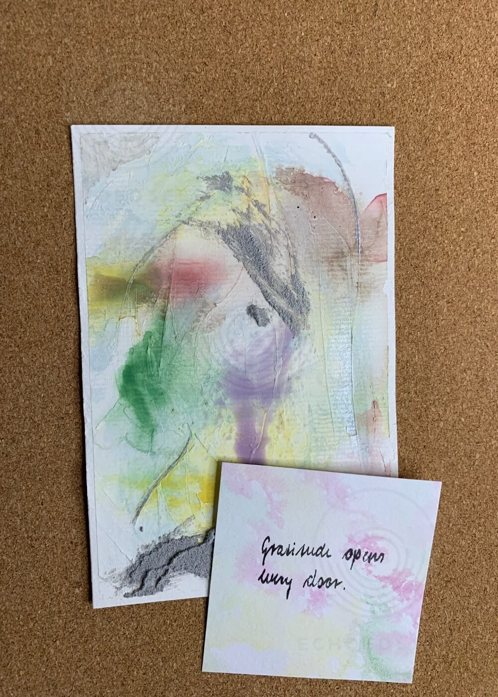 Abstract artwork "Between the Seconds No. 1" in green, yellow, purple and grey with a handwritten affirmation card reading "Gratitude opens every door", displayed on kraft paper.