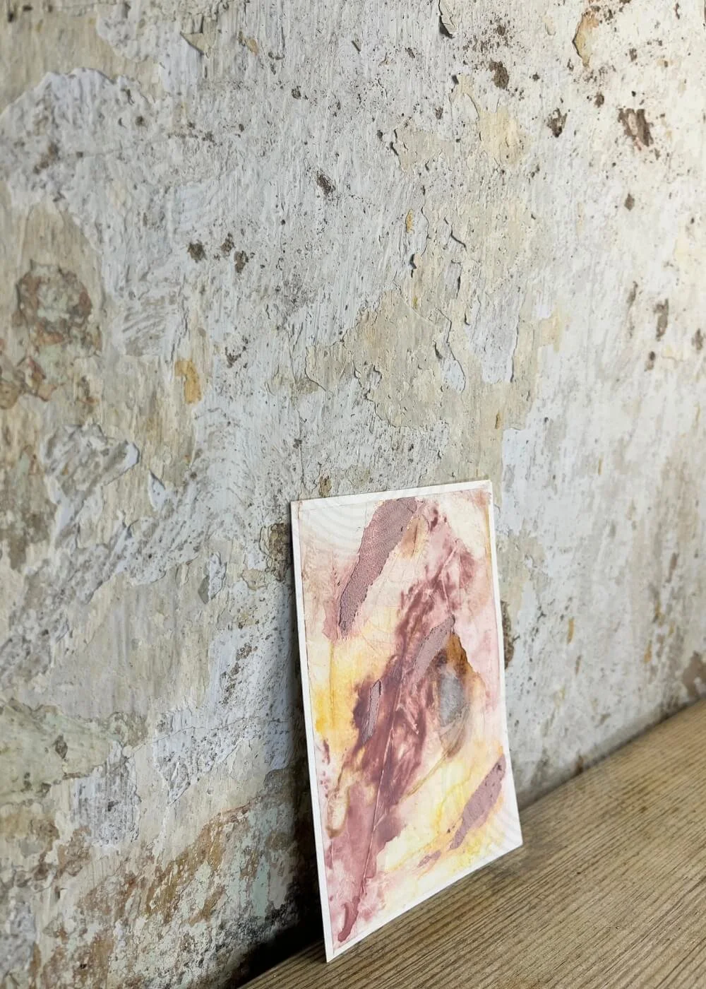 Side view of “Held by Myself No. 4” – tactile healing artwork in rose, golden, and earthy hues leaning gently against a rustic wall.