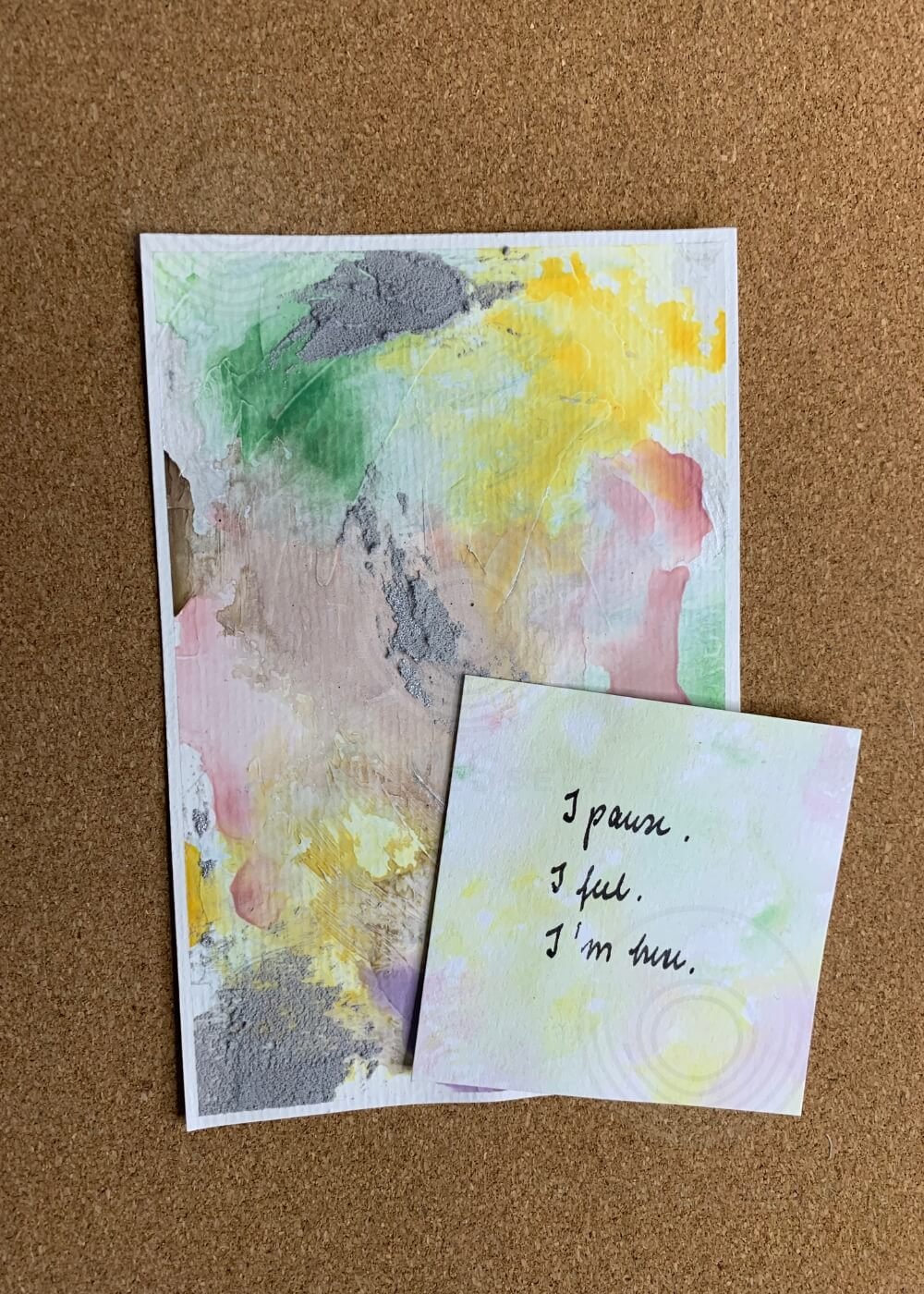 Abstract artwork "Between the Seconds No. 6" in pastel tones of yellow, green, and muted pink with textured grey, displayed with an affirmation card reading “I pause. I feel. I’m here.”