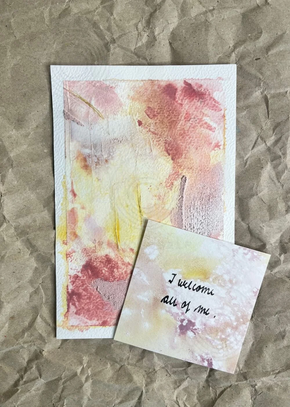 Abstract art card "Held by myself No. 9" in warm rosé and golden hues with an affirmation card reading “I welcome all of me.”