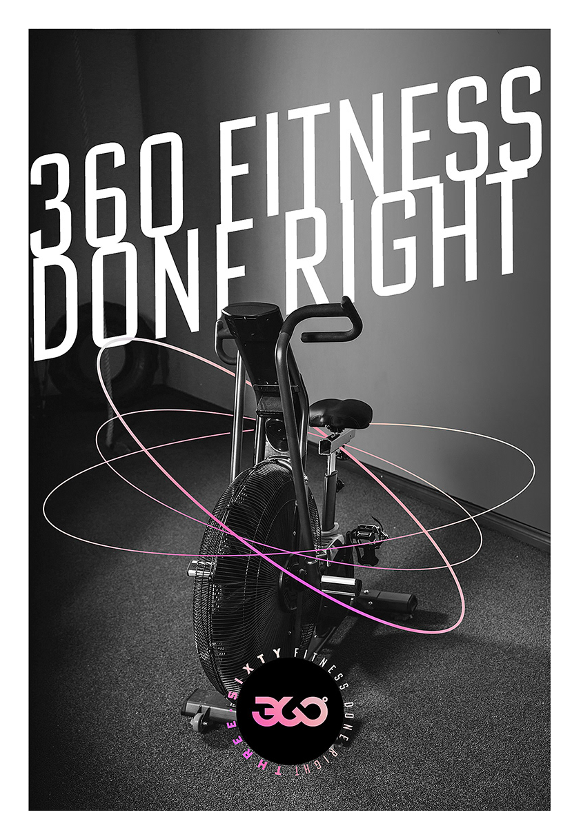 Bicicleta estática en un gimnasio con fondo de pared gris, con letras grandes blancas que dicen '360 fitness' y un logotipo circular con letras entrelazadas en la parte inferior.