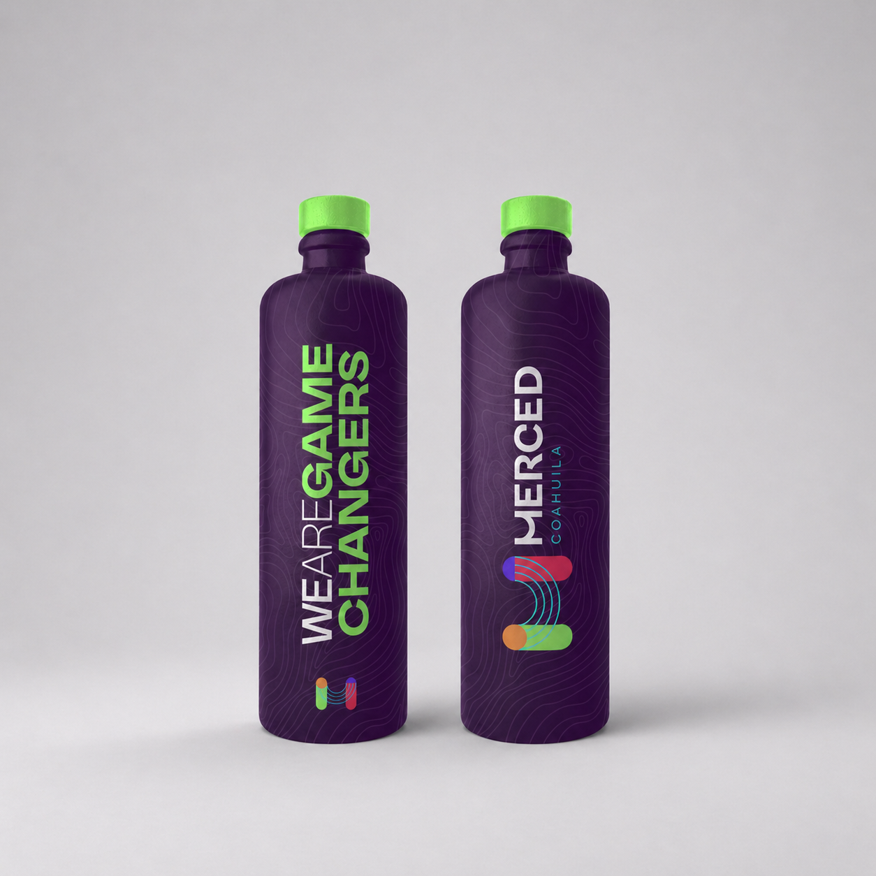 Dos botellas de agua con etiquetas que dicen 'We Are Game Changers' y 'Merced Coahuila' en fondo gris claro.